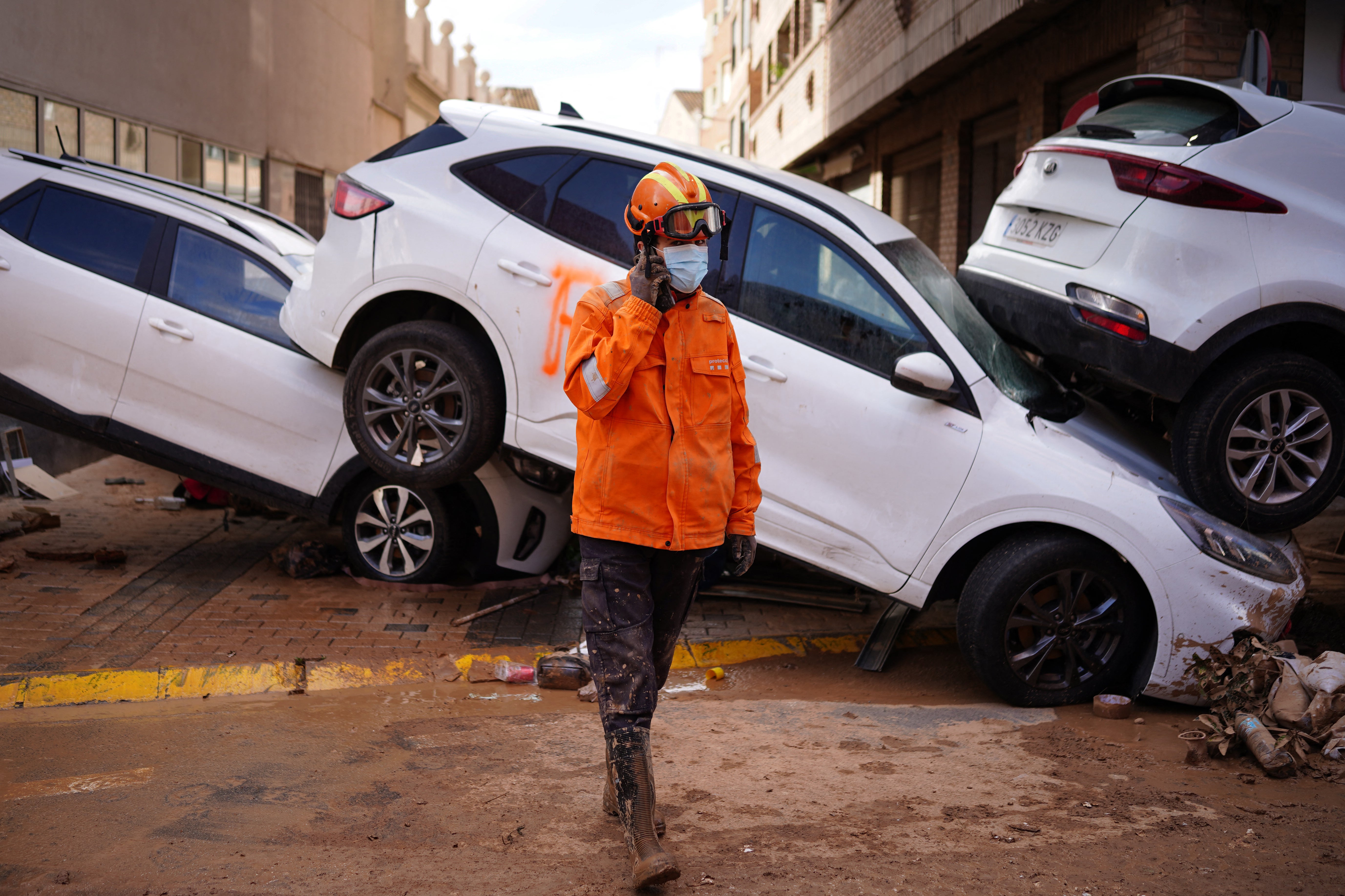 A Civil Protection member walks past flood damaged vehicles in Sedavi, in the region of Valencia, eastern Spain, on November 3, 2024, in the aftermath of devastating deadly floods