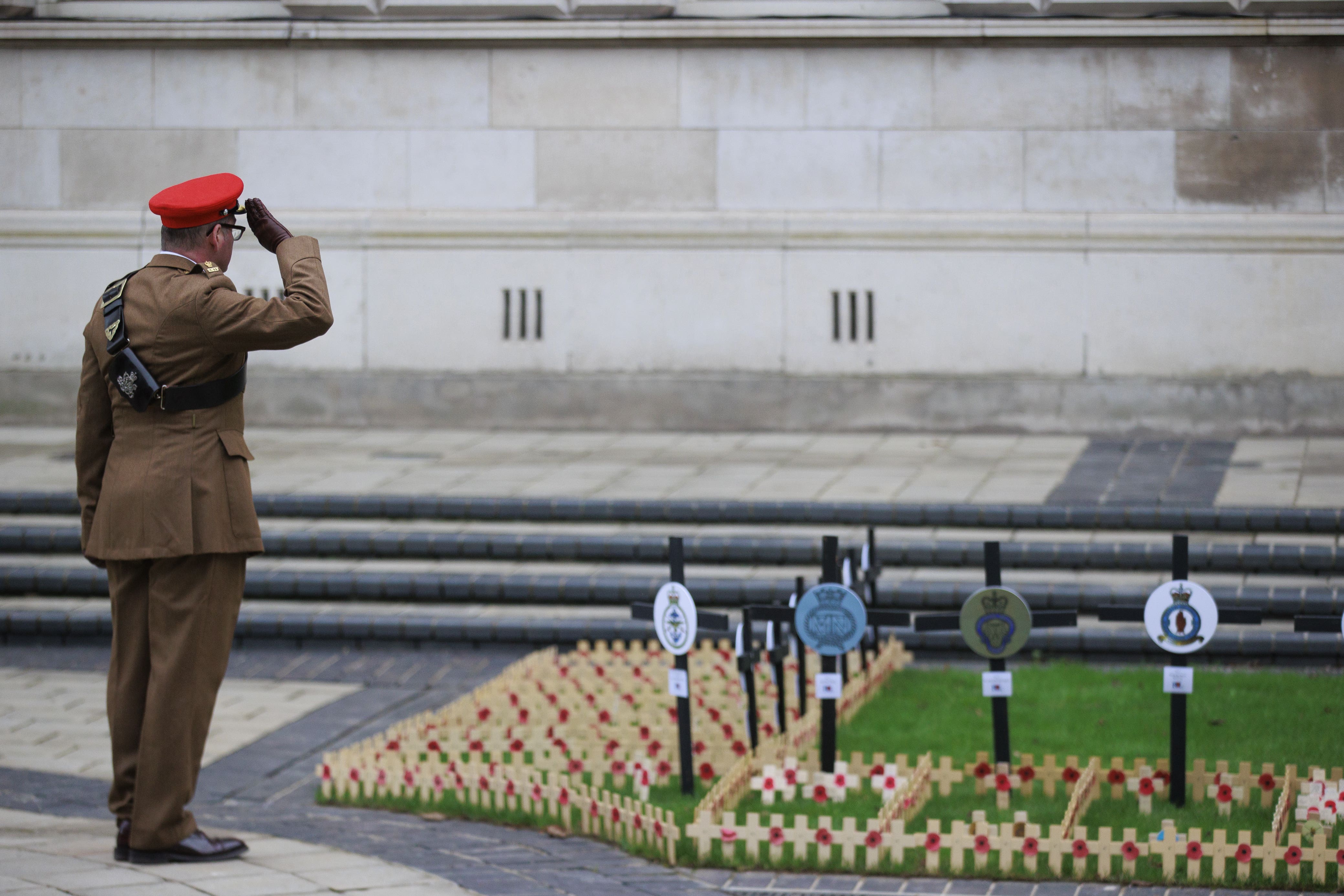 A member of the armed forces salutes after placing Remembrance tributes at the opening of the Field of Remembrance at Belfast City Hall (Liam McBurney/PA)