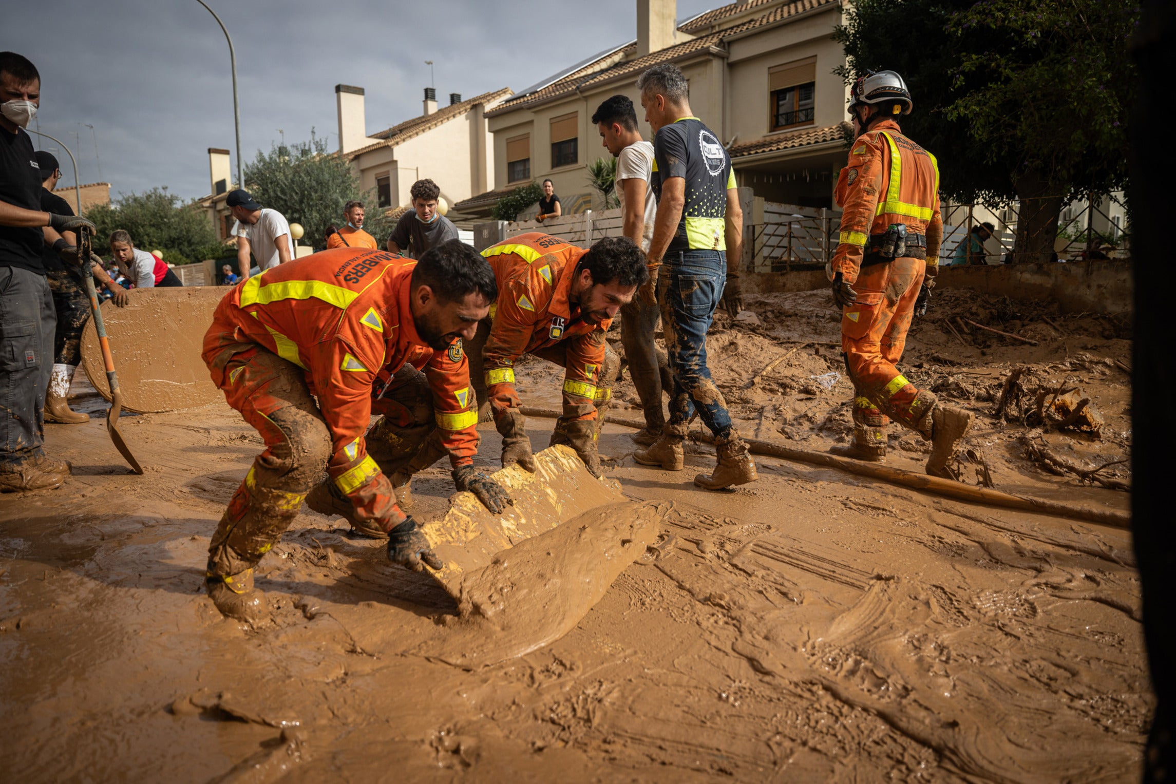 Volunteer firefighters in Valencia are working to clean the streets of mud using materials they can find