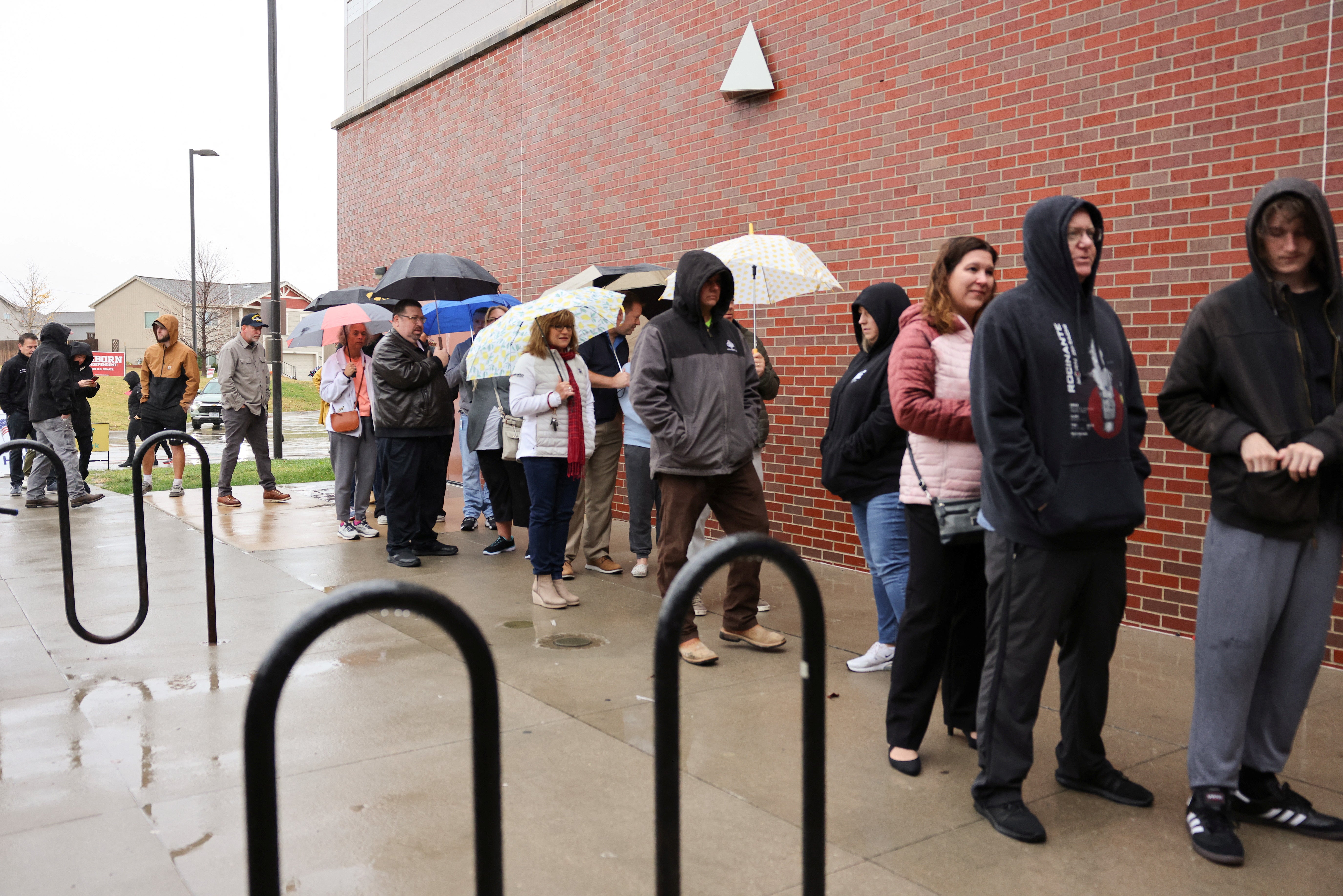 Voters, including Senate candidate Dan Osborn line up in the rain to vote for the presidential election in Omaha, Nebraska, on Tuesday. Rain impacted polling sites in Texas, as well.