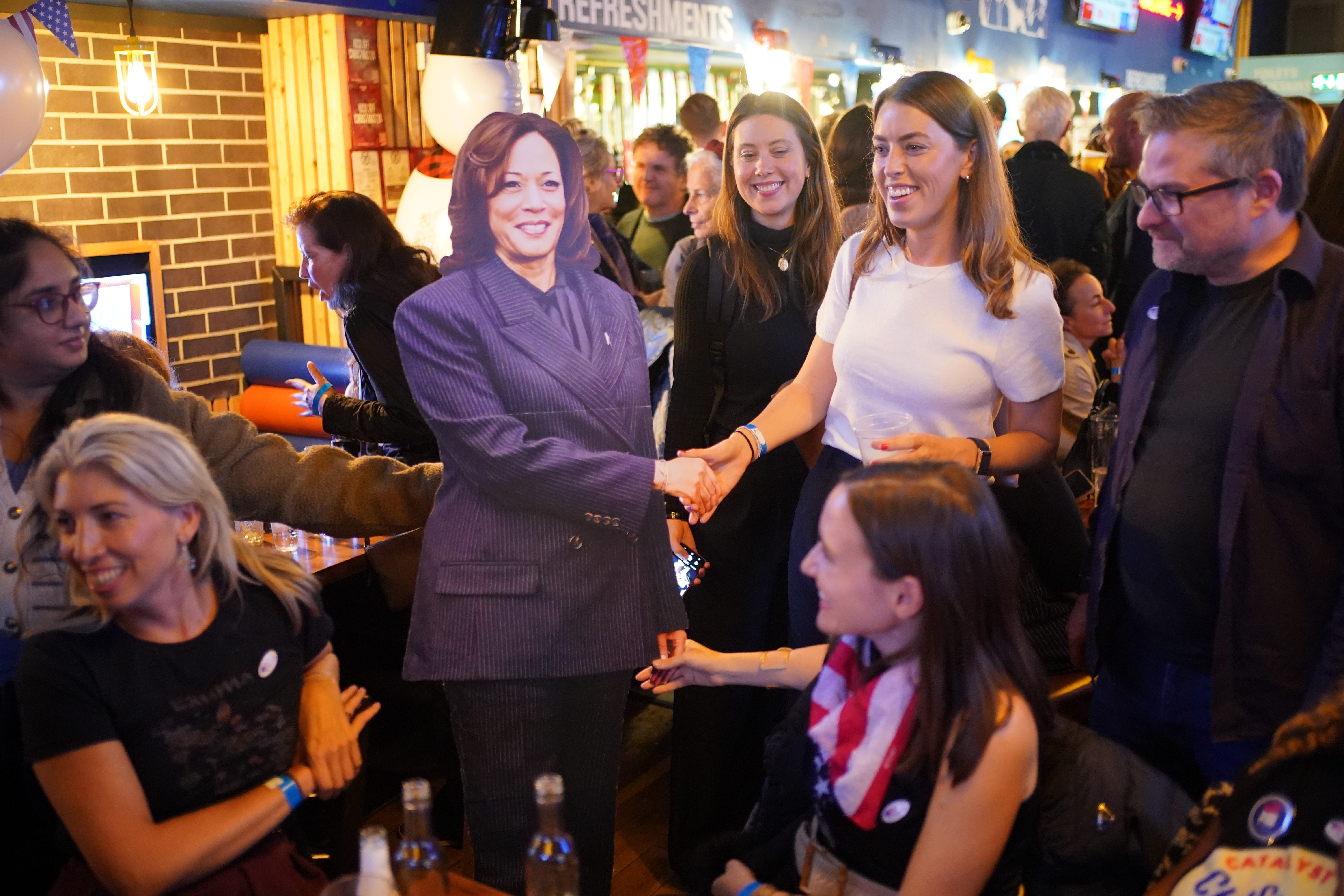 People pose for photos with a cardboard cutout of Kamala Harris (Yui Mok / PA).