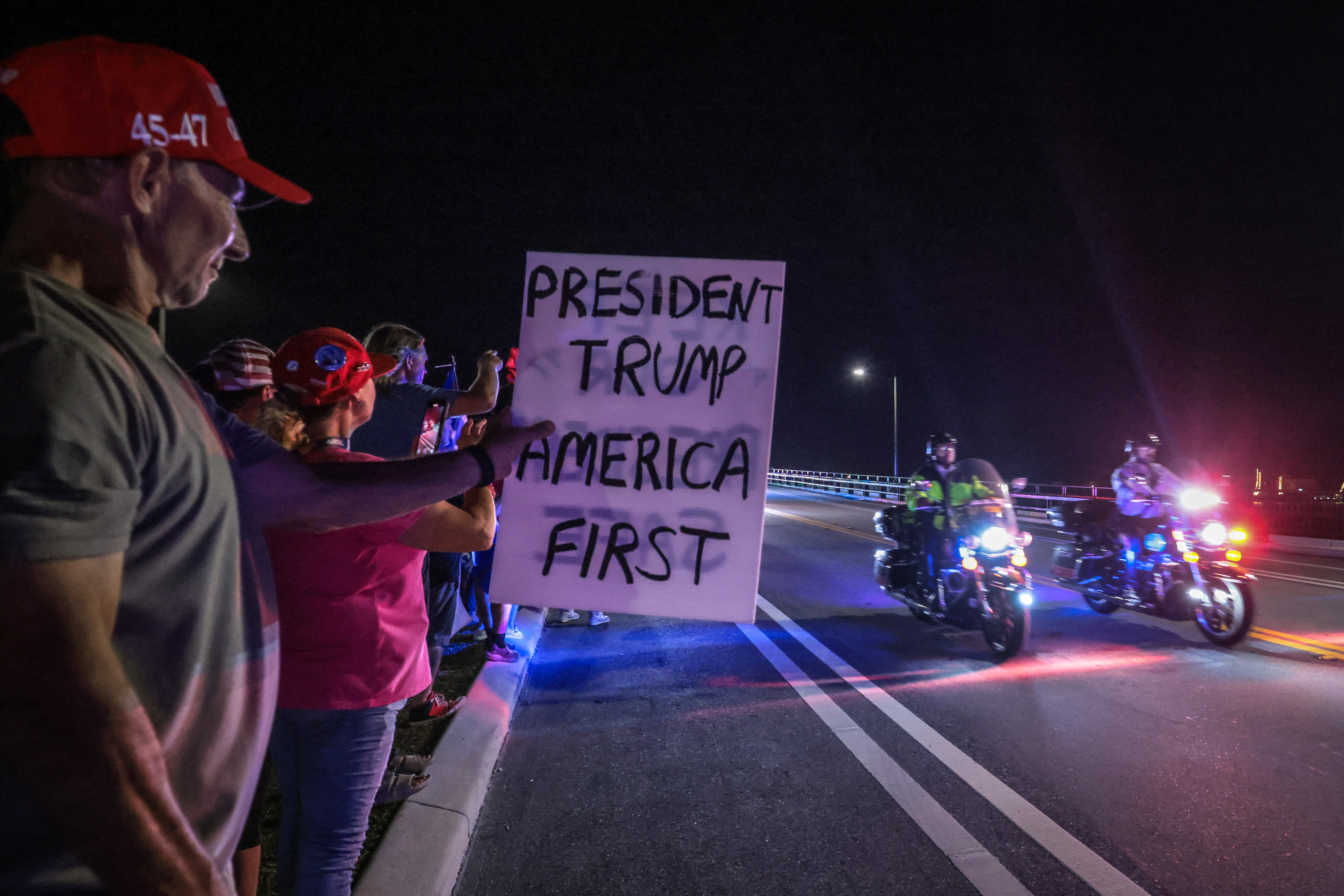 Supporters of former US president and Republican presidential candidate Donald Trump gesture as a motorcade drives near his Mar-a-Lago resort in Palm Beach, Florida, on Election Day, early on November 6, 2024.