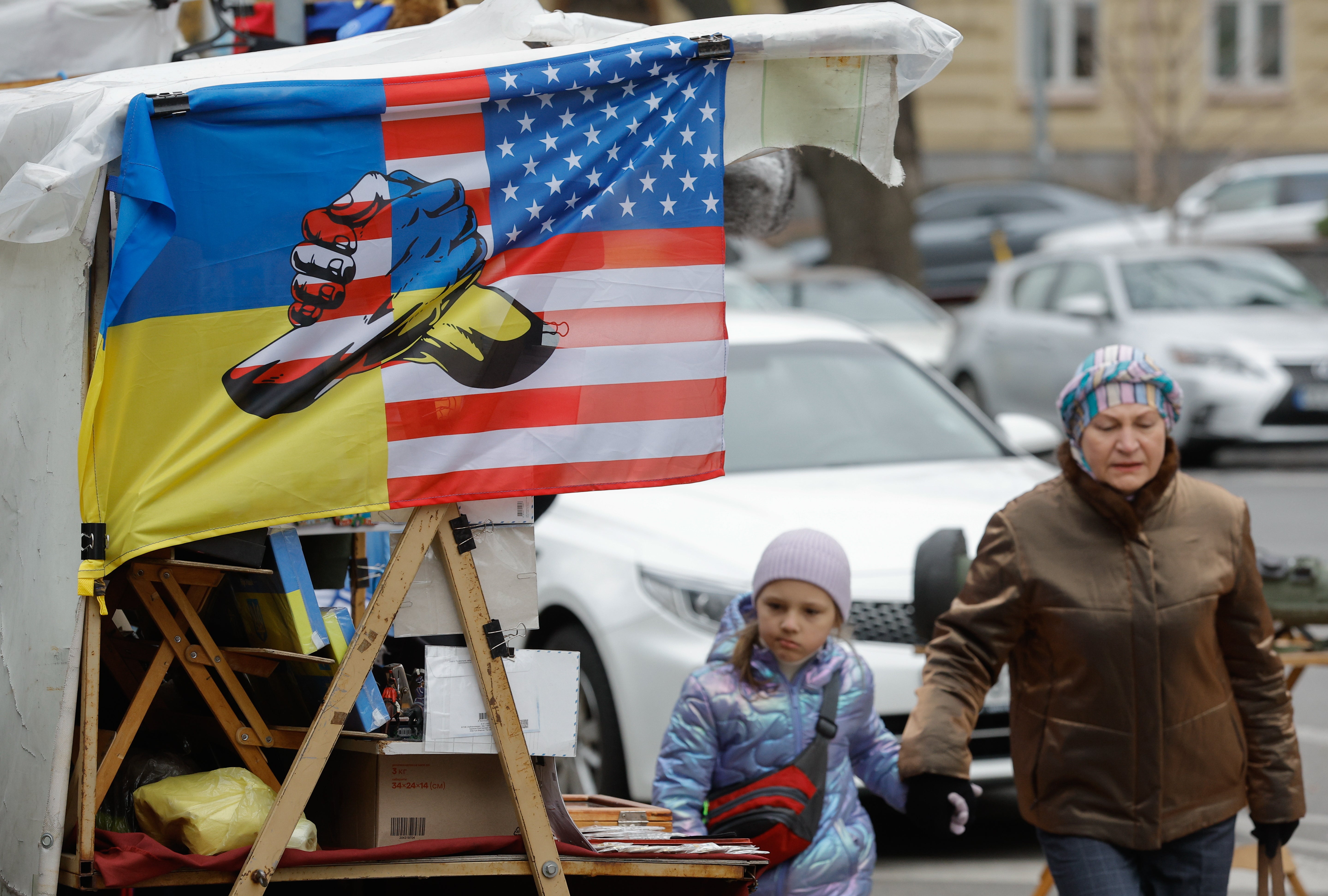 Ukrainians pass a souvenir stall with a flag depicting Ukrainian and US flags, in downtown Kyiv, Ukraine