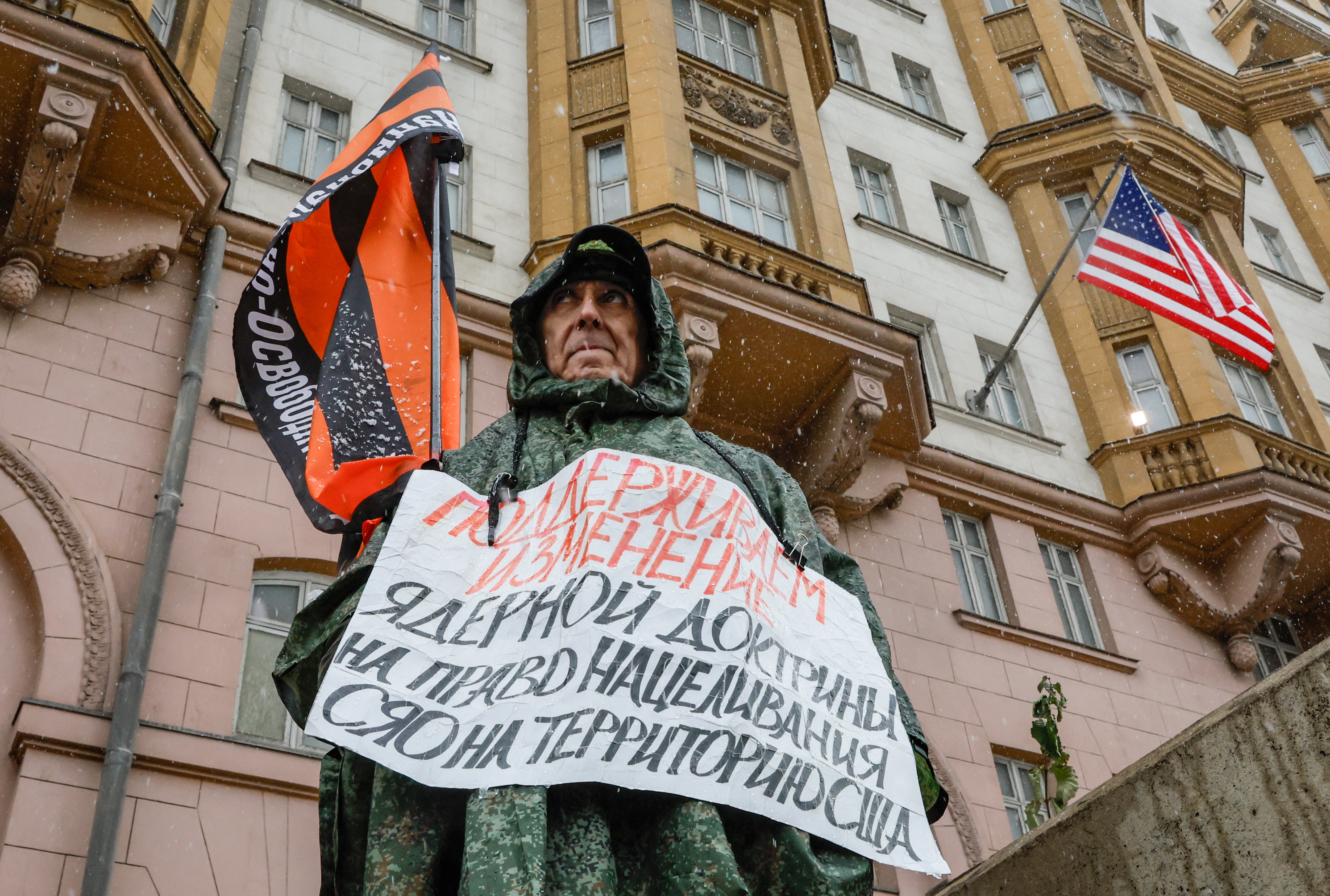 A man with a flag carrying the name of the organisation 'National Liberation Movement', with a poster reading 'We support changing the nuclear doctrine to allow for the right to target strategic nuclear weapons at US territory', near the US embassy in Moscow, Russia