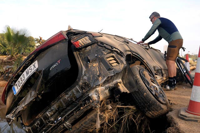 <p>Jorge Tarazona attaches a poster to a car in Paiporta, Valencia, Spain</p>