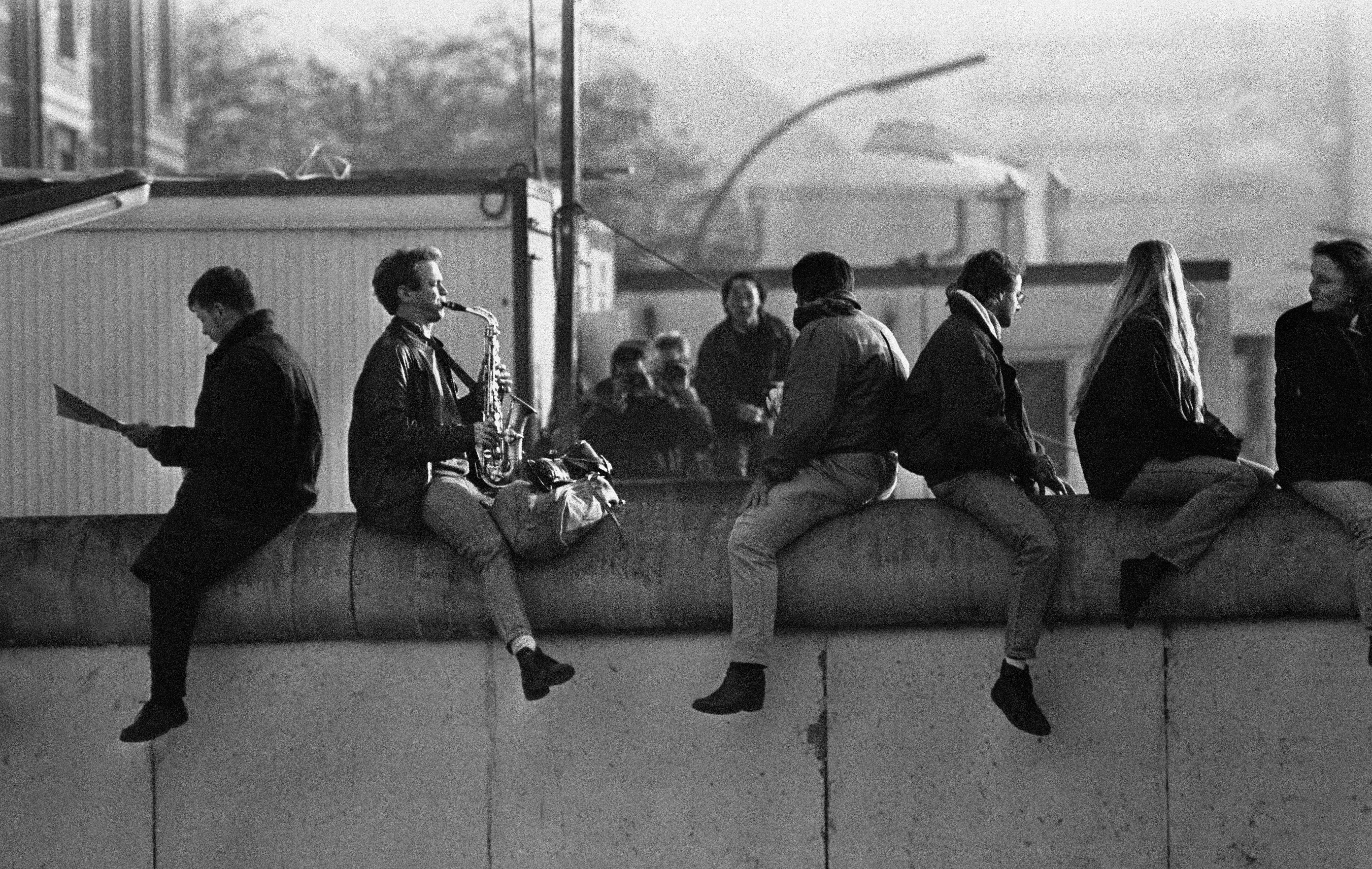 Musician Stephen Ellery sits on top of the Berlin Wall and plays ‘Misty’ by Erroll Garner on his saxophone