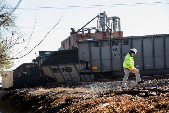 <p>A Norfolk Southern worker walks next to the scene of a multi-car coal train derailment in 2017. </p>