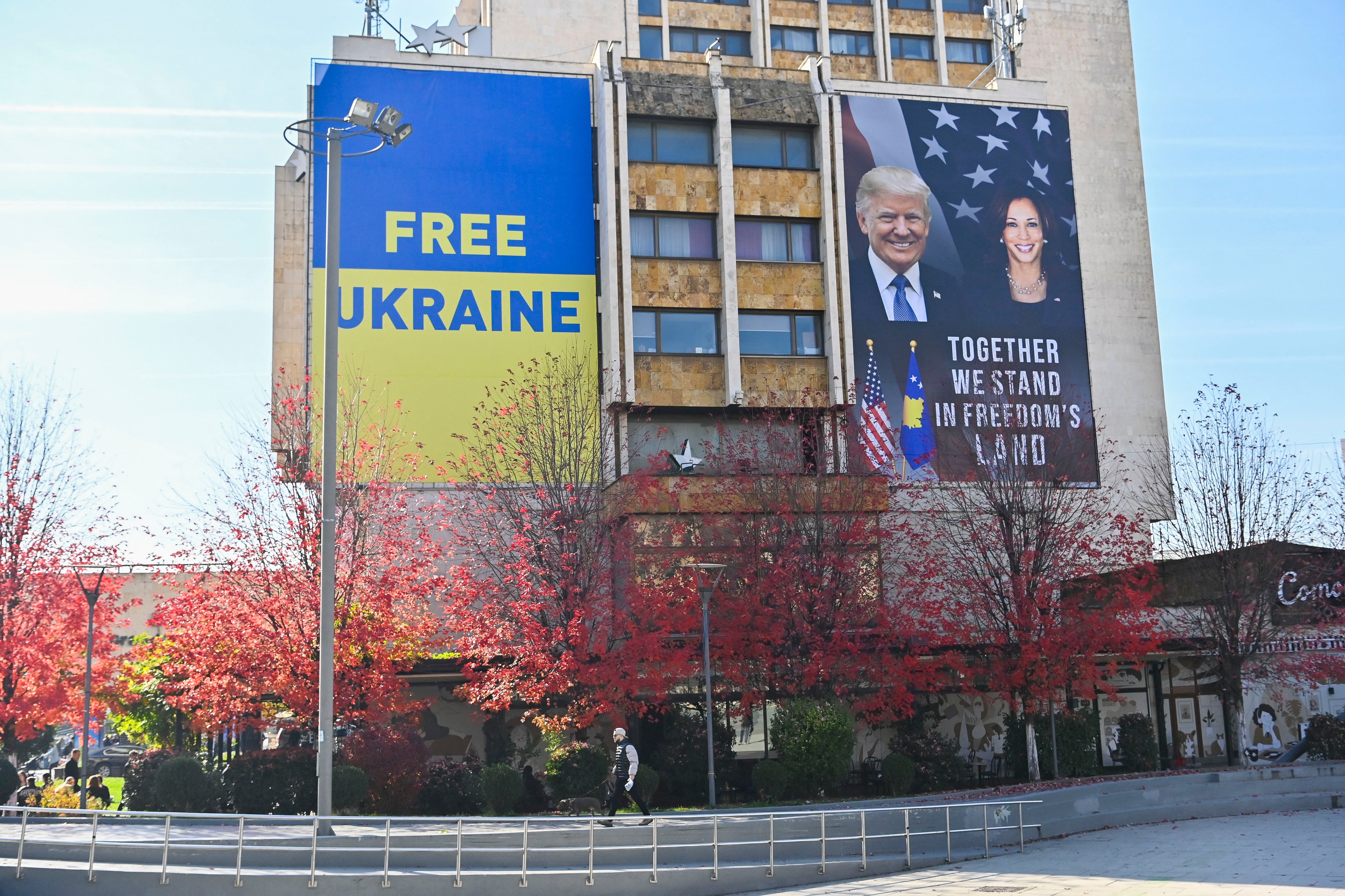 A large banner bearing the portrait of Kamala Harris and Donald Trump is displayed next to a banner reading ‘Free Ukraine’ in Kyiv