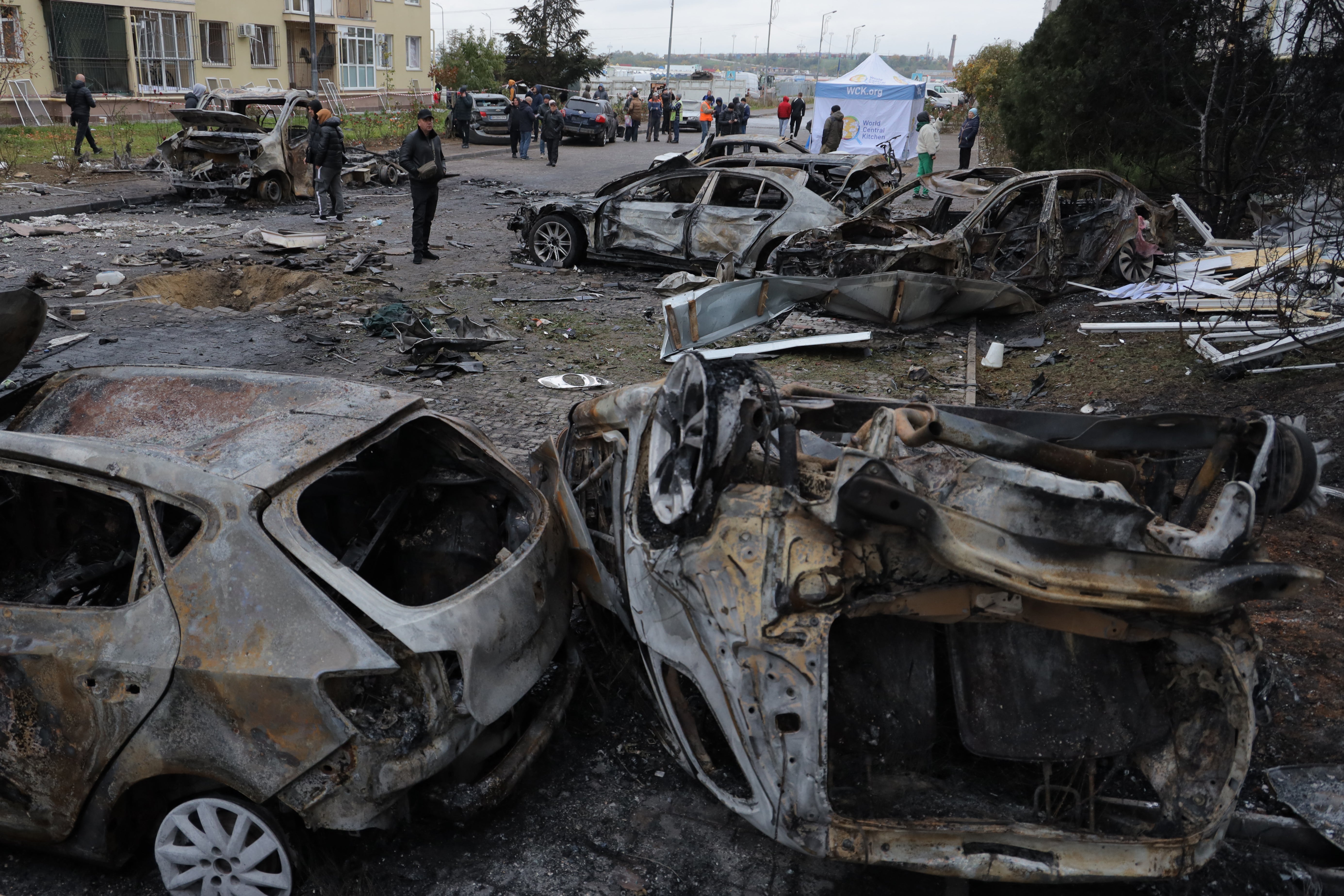 Local residents inspect burnt-out cars in the courtyard of a residential building following a drone attack in Odesa