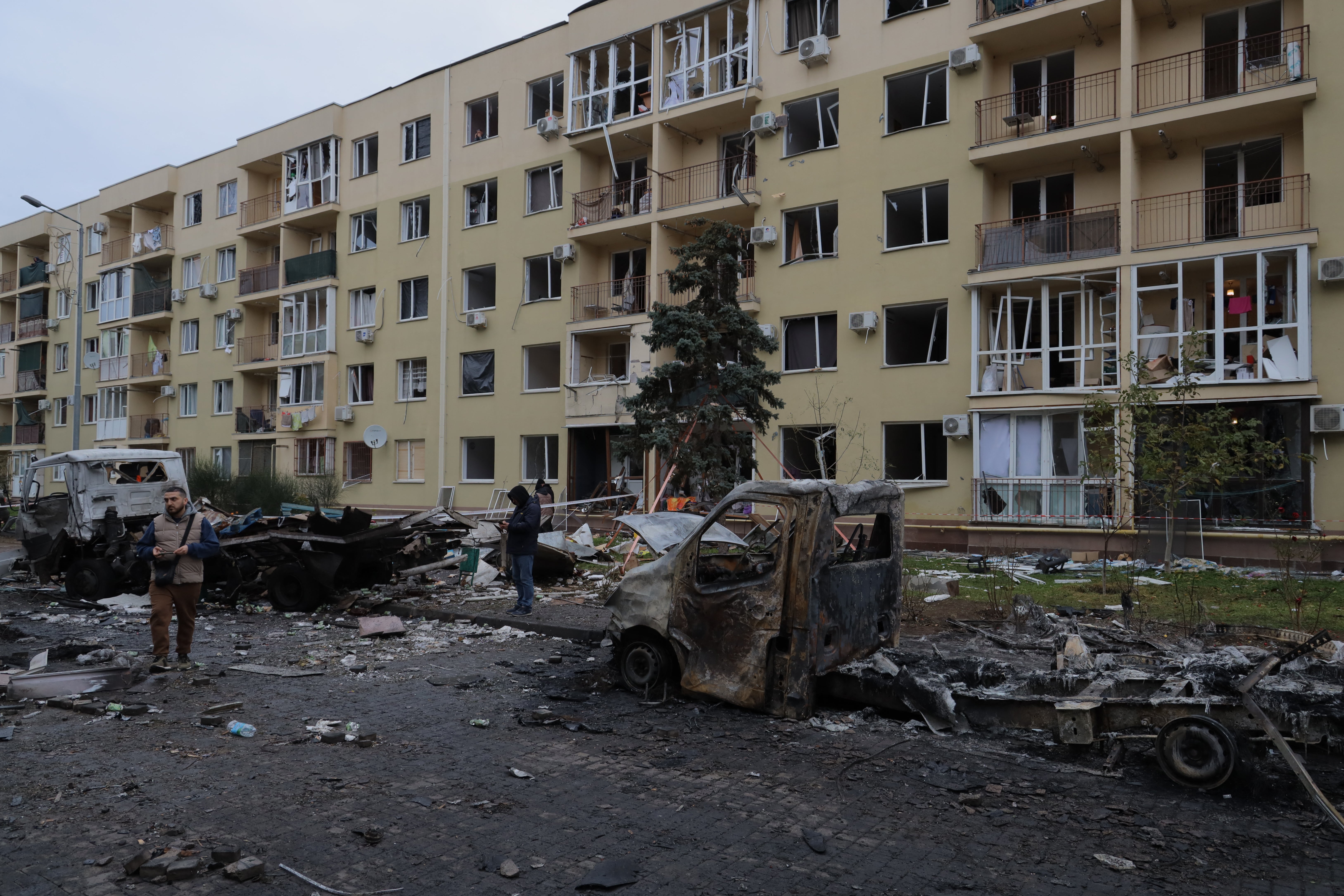 Local residents inspect burnt-out cars in the courtyard of a residential building following a drone attack in Odesa