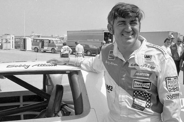 <p>Bobby Allison stands beside his car and talks with the press after winning the pole position during qualifying for the 500 mile grand national stock car race at Pocono Raceway, August 2, 1975, in Long Pond, Pennsylvania</p>