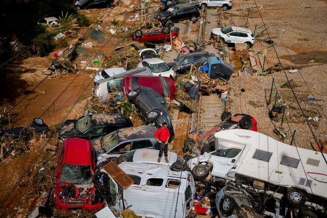 <p>A man stands among flooded cars piled up in Valencia, Spain</p>