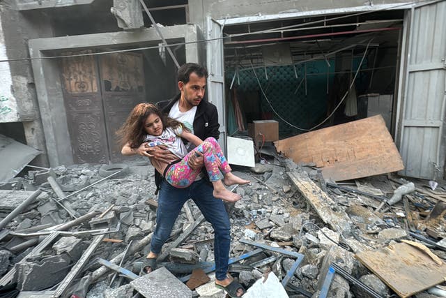 <p>A Palestinian man carries away an injured child from a home that was hit in an Israeli strike on the Jabalia refugee camp in the northern Gaza Strip</p>