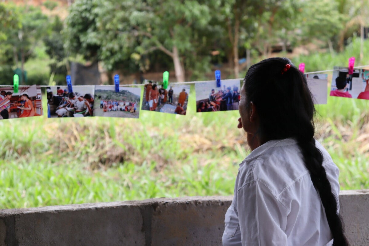 An Indigenous woman looks at images from a basic income workshop; Patricia Quiñones, who is heading the no-strings-attached cash program for climate charity Cool Earth, says that economic pressure is one of the main ‘drivers of deforestation, alongside illegal mining and logging'