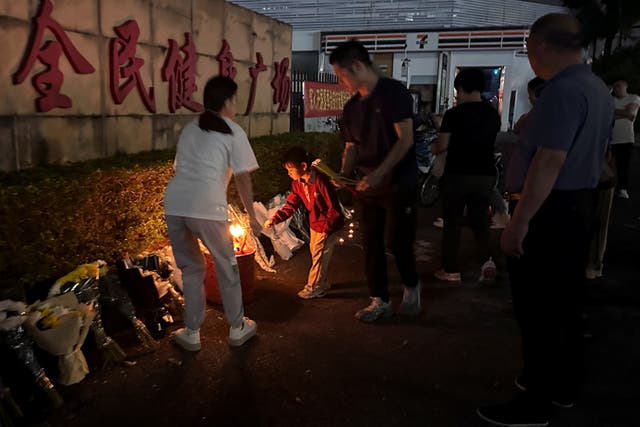 <p>People burn incense near floral tributes placed outside a sports centre where a deadly hit-and-run attack took place, in Zhuhai</p>