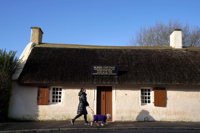 A person walks a dog past Burns Cottage in Alloway, Ayrshire, the birth place of the poet Robert Burns (Andrew Milligan/PA)