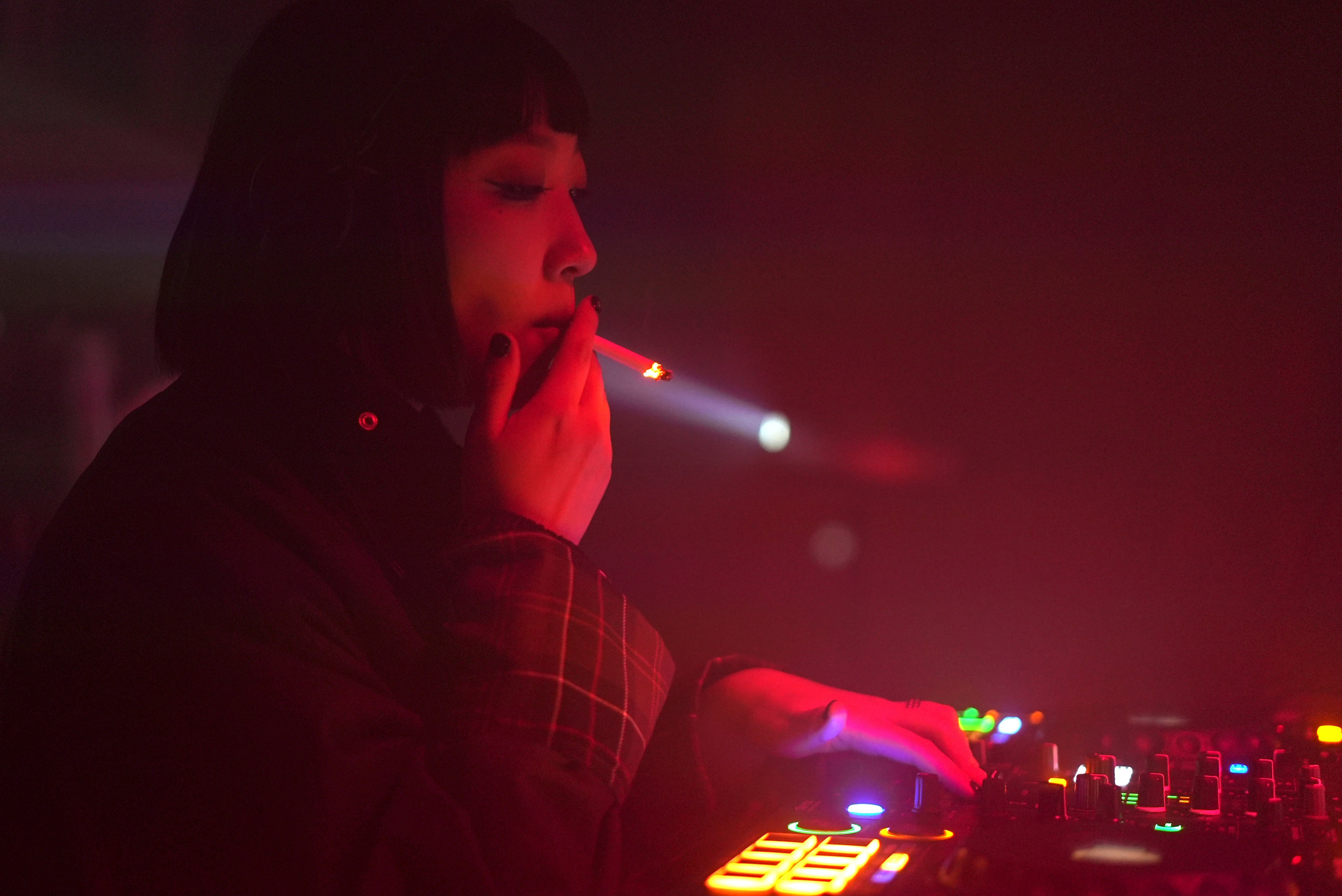 A DJ who goes by the stage name Kuro’ smokes a cigarette as she plays music in Changchu