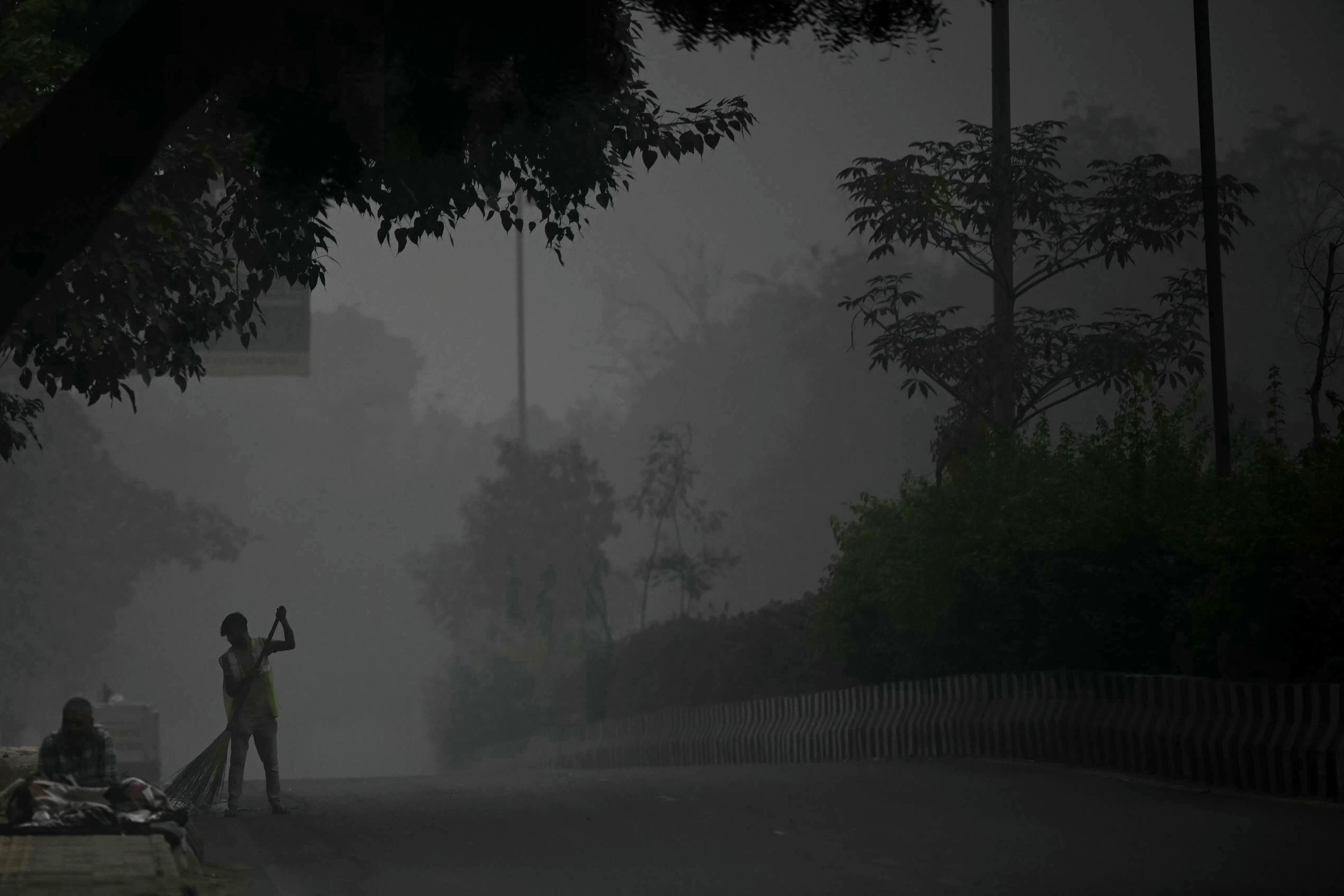 A sweeper brooms a road engulfed in smog in New Delhi