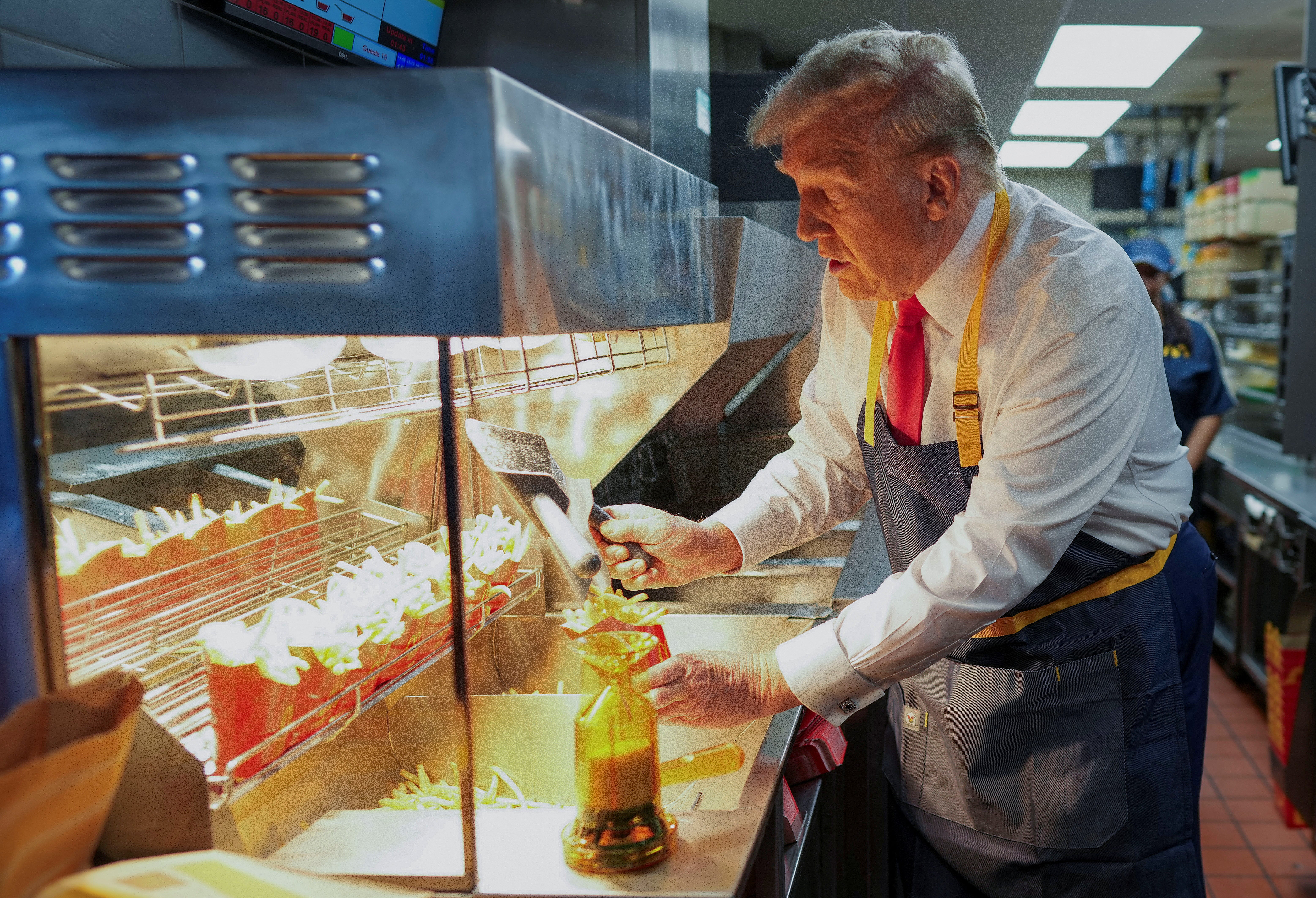 Donald Trump works behind the counter during a visit to McDonalds in Feasterville-Trevose, Pennsylvania, U.S. October 20, 2024. He has become famous for his own love of fast food