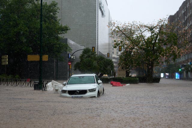 <p>A car is partly submerged in flood waters on Wednesday in Malaga, Spain</p>