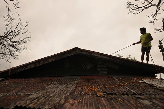 <p>A resident reinforces the roof of his house in Santa Ana in Cagayan province of northern Philippines as they Usagi approaches on 14 November 2024</p>