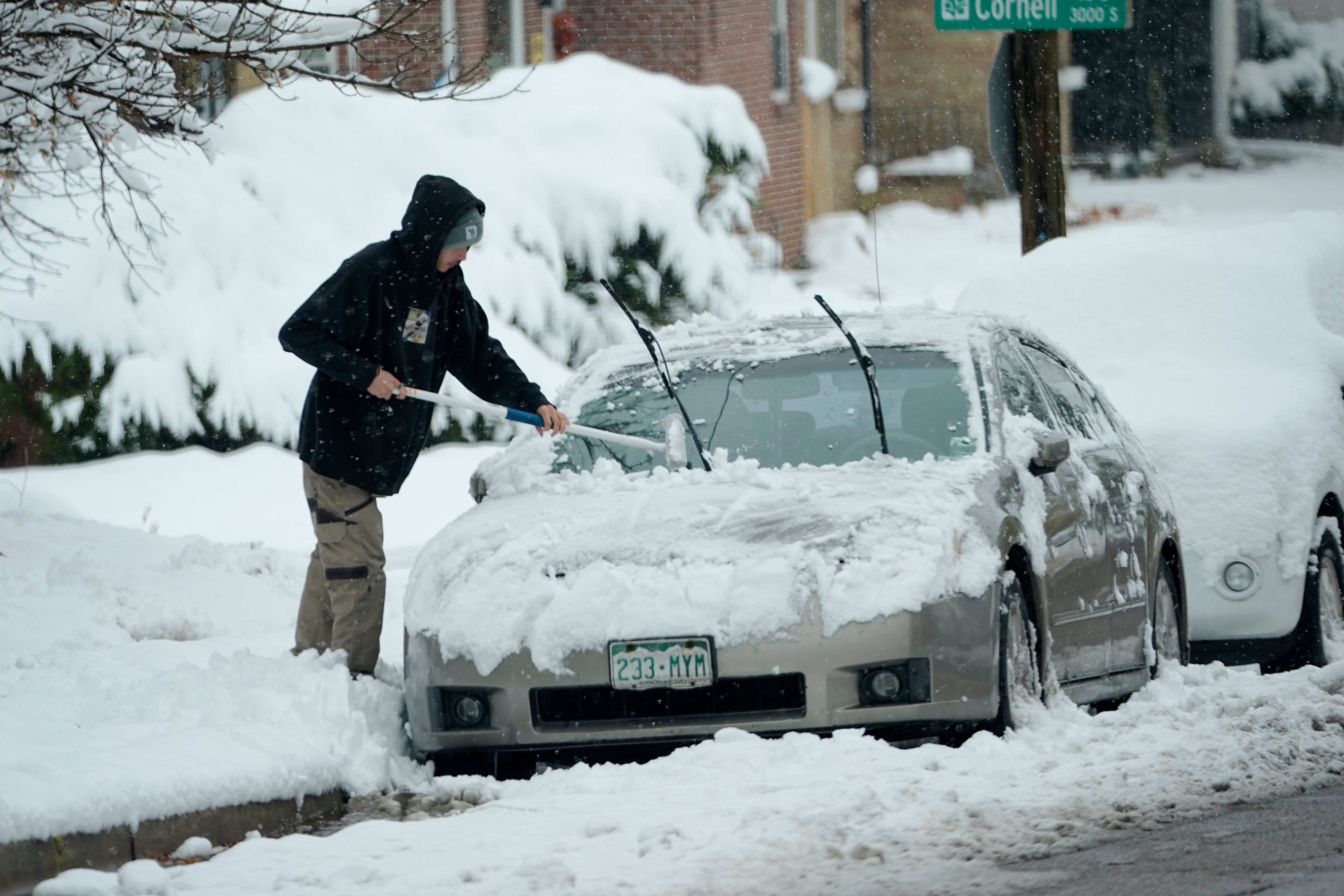 A person clears snow off of a car in Englewood, Colorado, last week. The state had its first snowstorm of the season and more is expected this week.