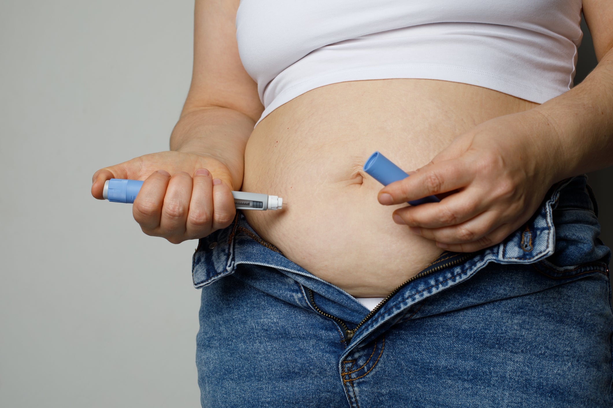 A woman injects a weight loss drug into her stomach. The study’s contributors say semaglutide and weight loss drugs alone will not be enough to solve America’s obesity epidemic.