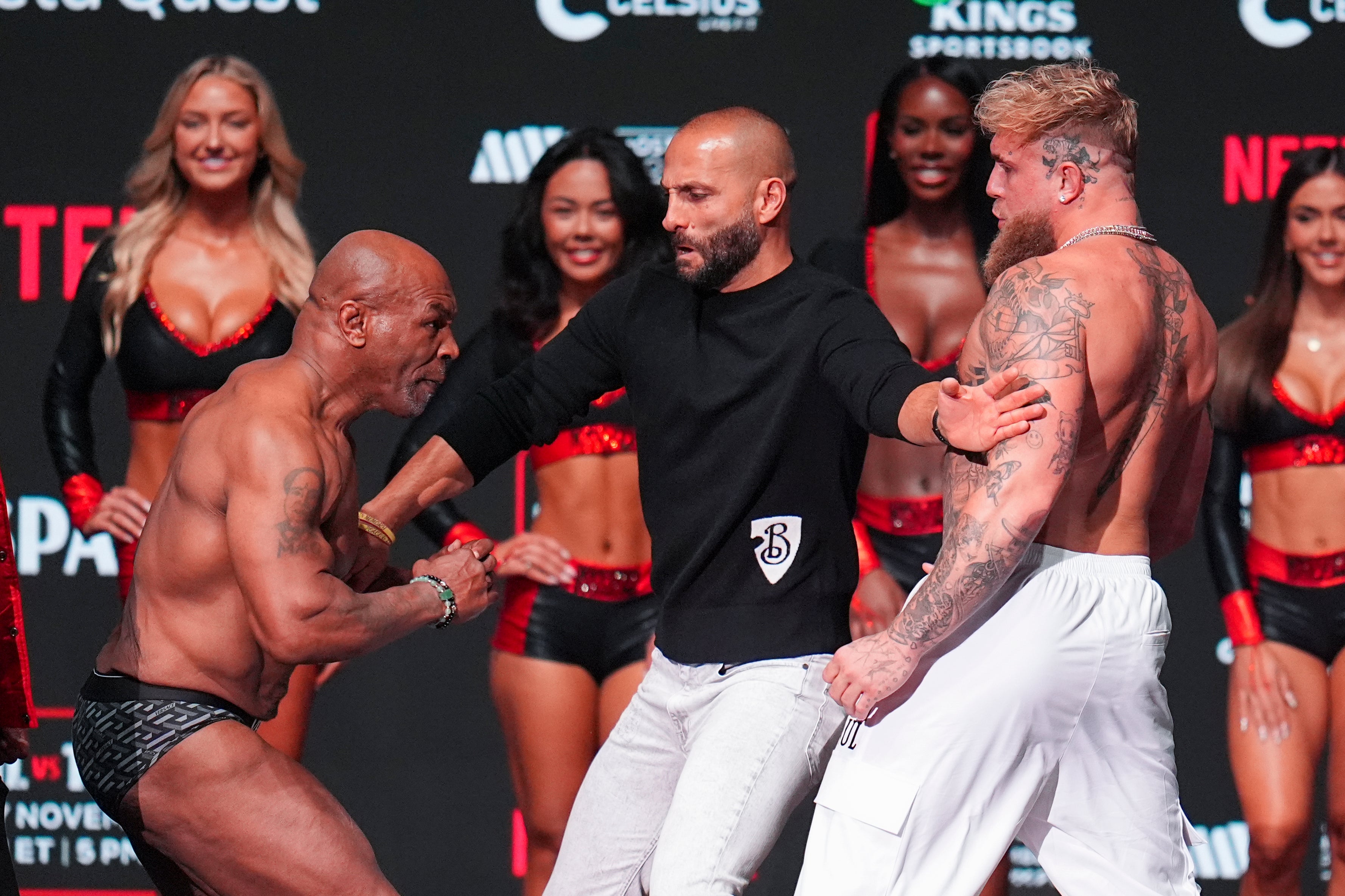 Promoter Nakisa Bidarian, centre, steps in the way of Mike Tyson, left, after Tyson slapped Jake Paul (Julio Cortez/AP)