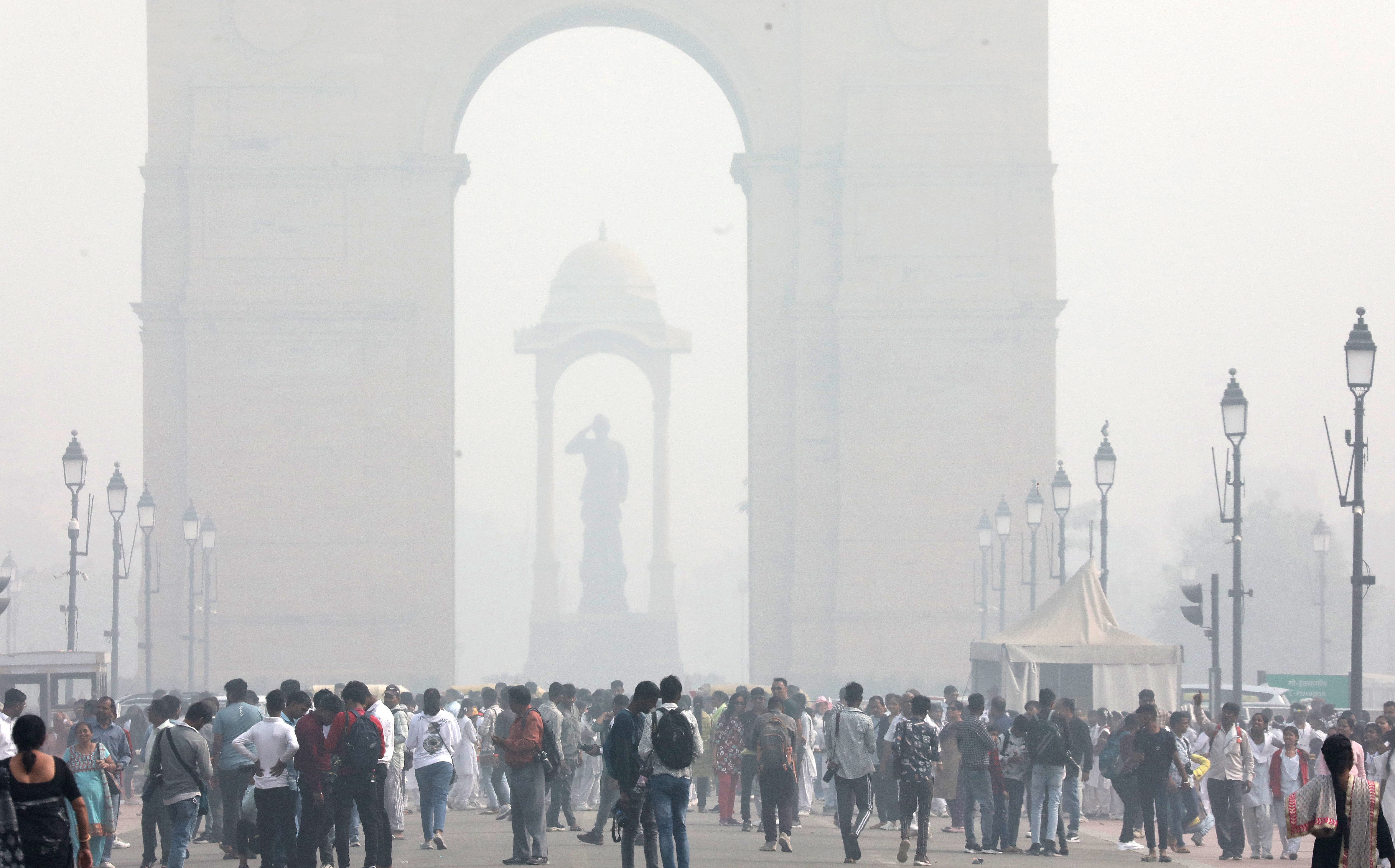 People walk near the India Gate as Delhi is covered in smog on 14 November 2024