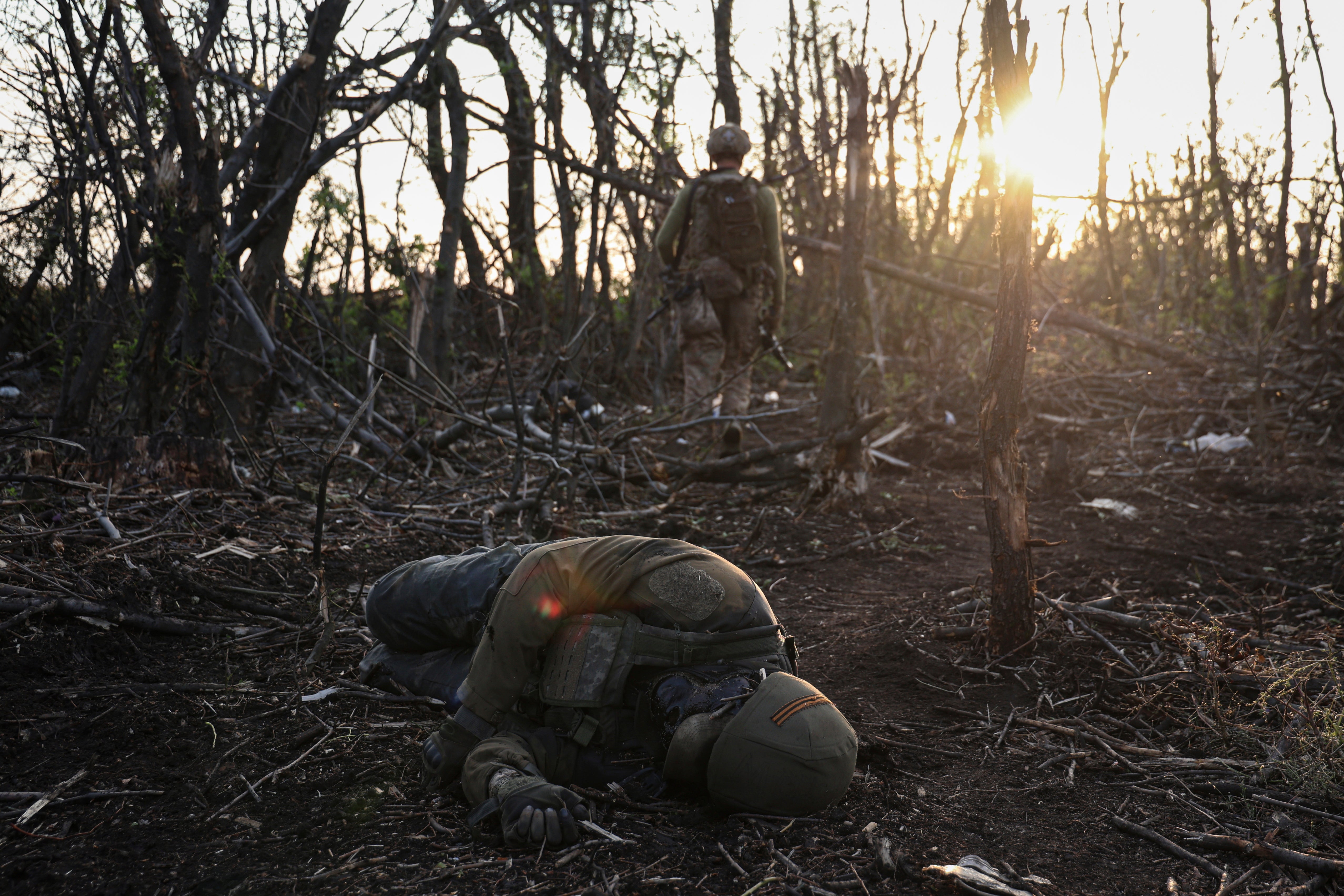 FILE - A Ukrainian assault unit commander passes by a dead Russian soldier