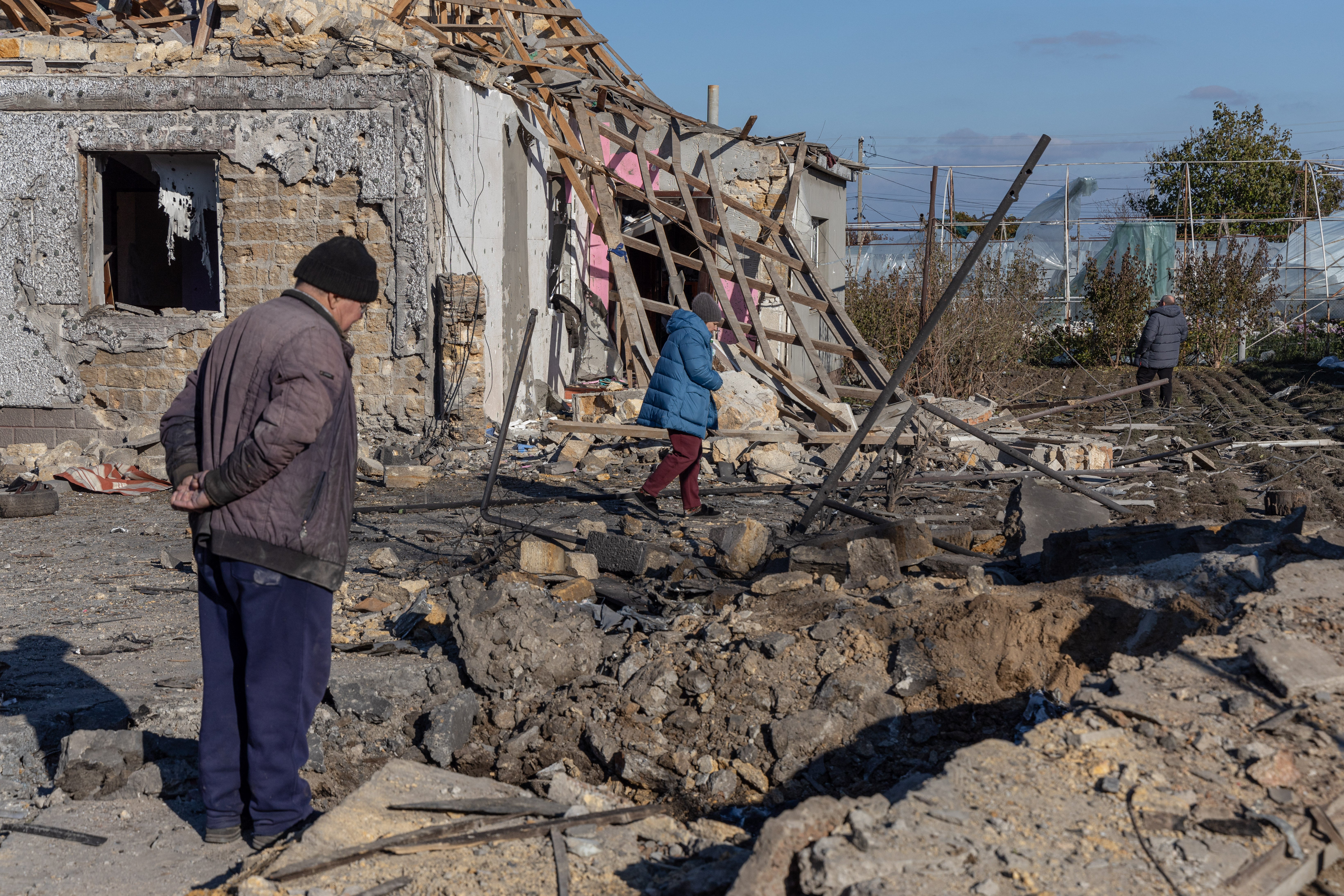 A local resident inspects a crater in the courtyard of a destroyed building following a missile attack at an undisclosed location in Odesa region