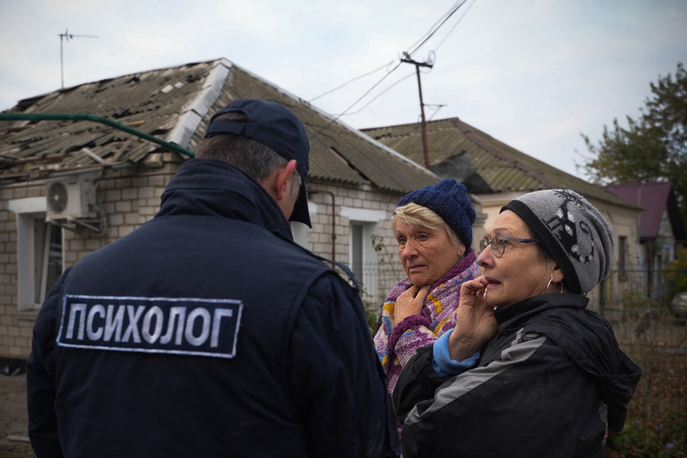 A Ukrainian officer speaks with local residents following a drone attack in Mykolaiv