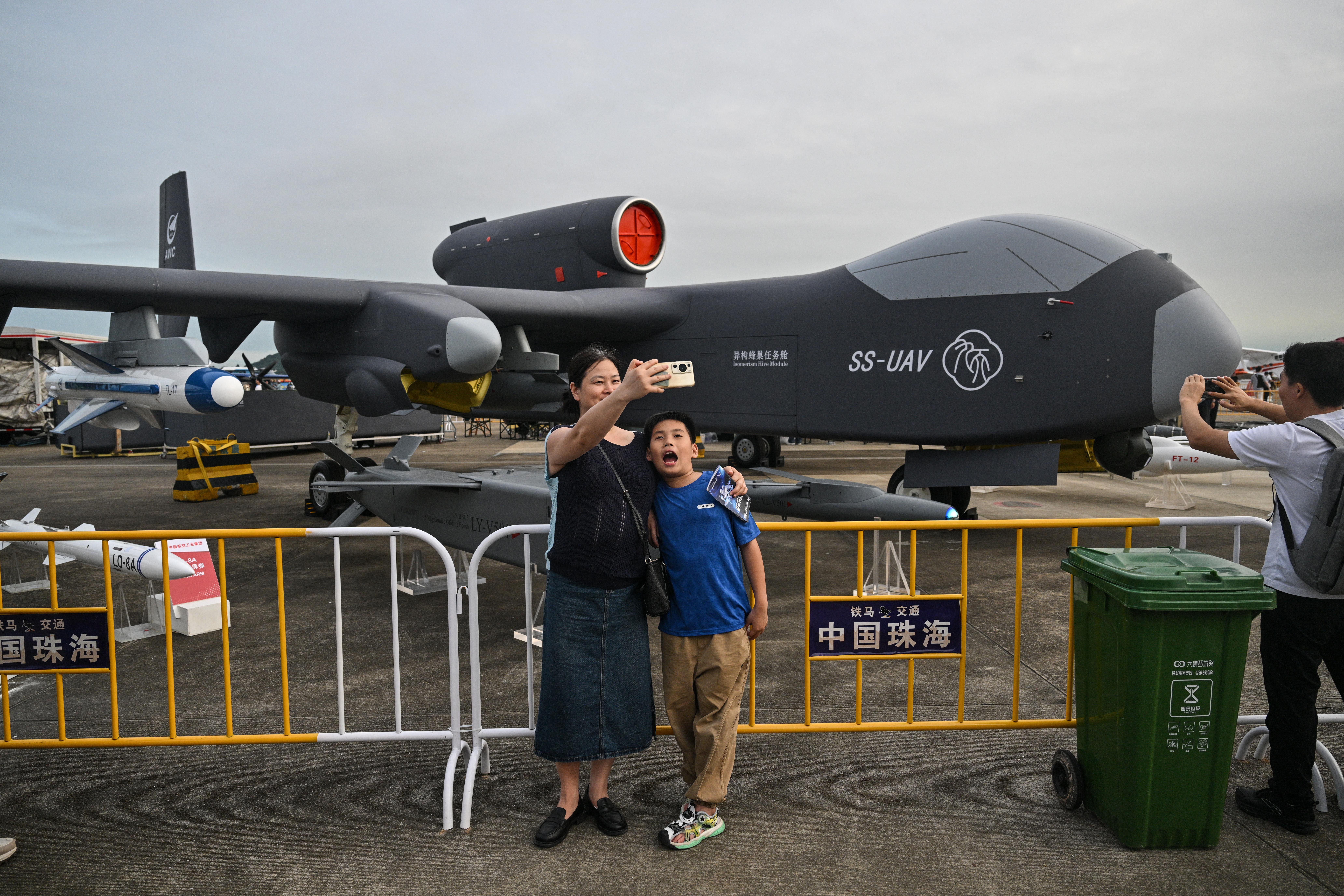 A woman takes a selfie next to a Jetank UAV during the 15th China International Aviation and Aerospace Exhibition in Zhuhai