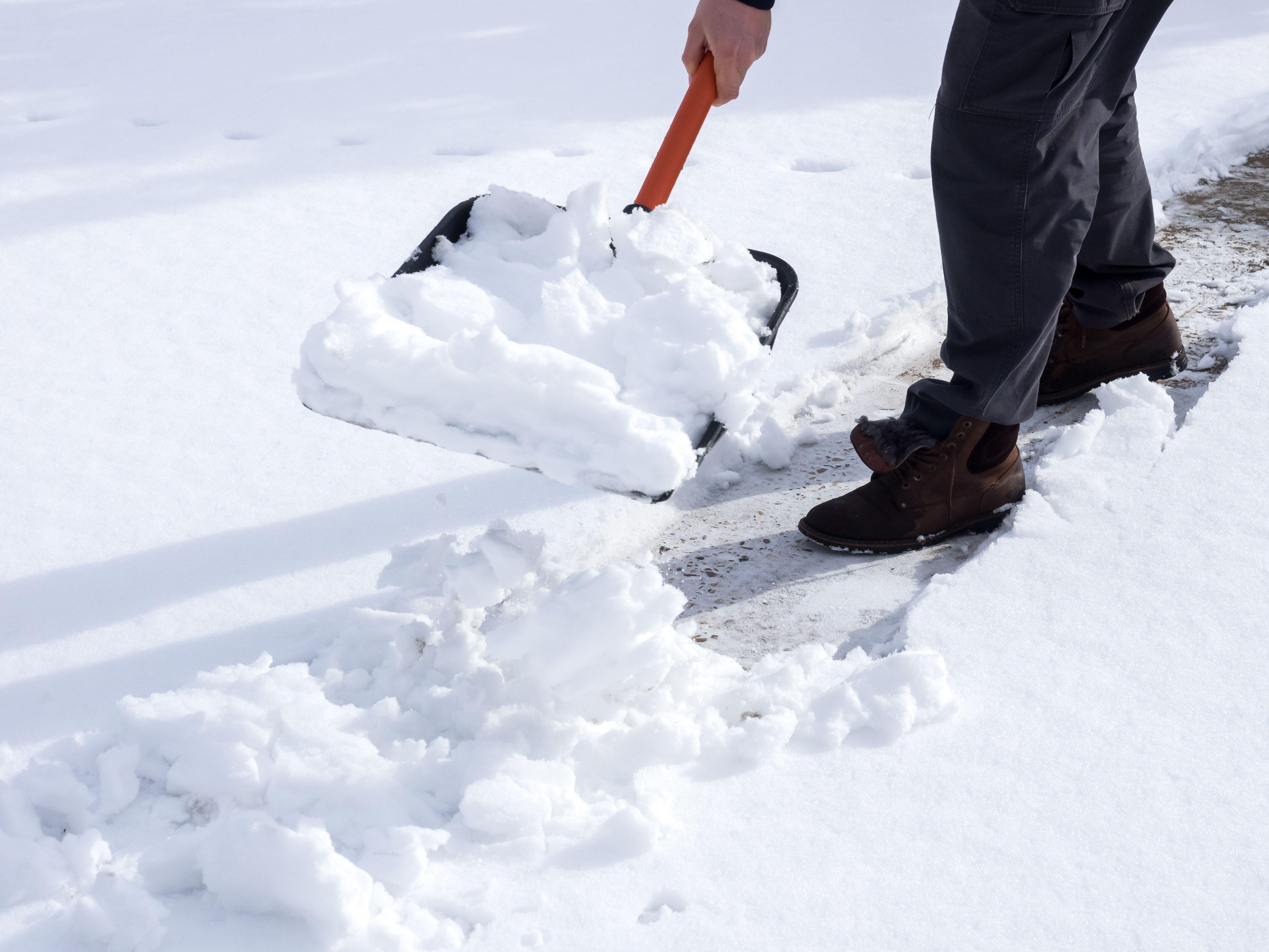 Close up image of a man shovelling snow in a garden (Alamy/PA)