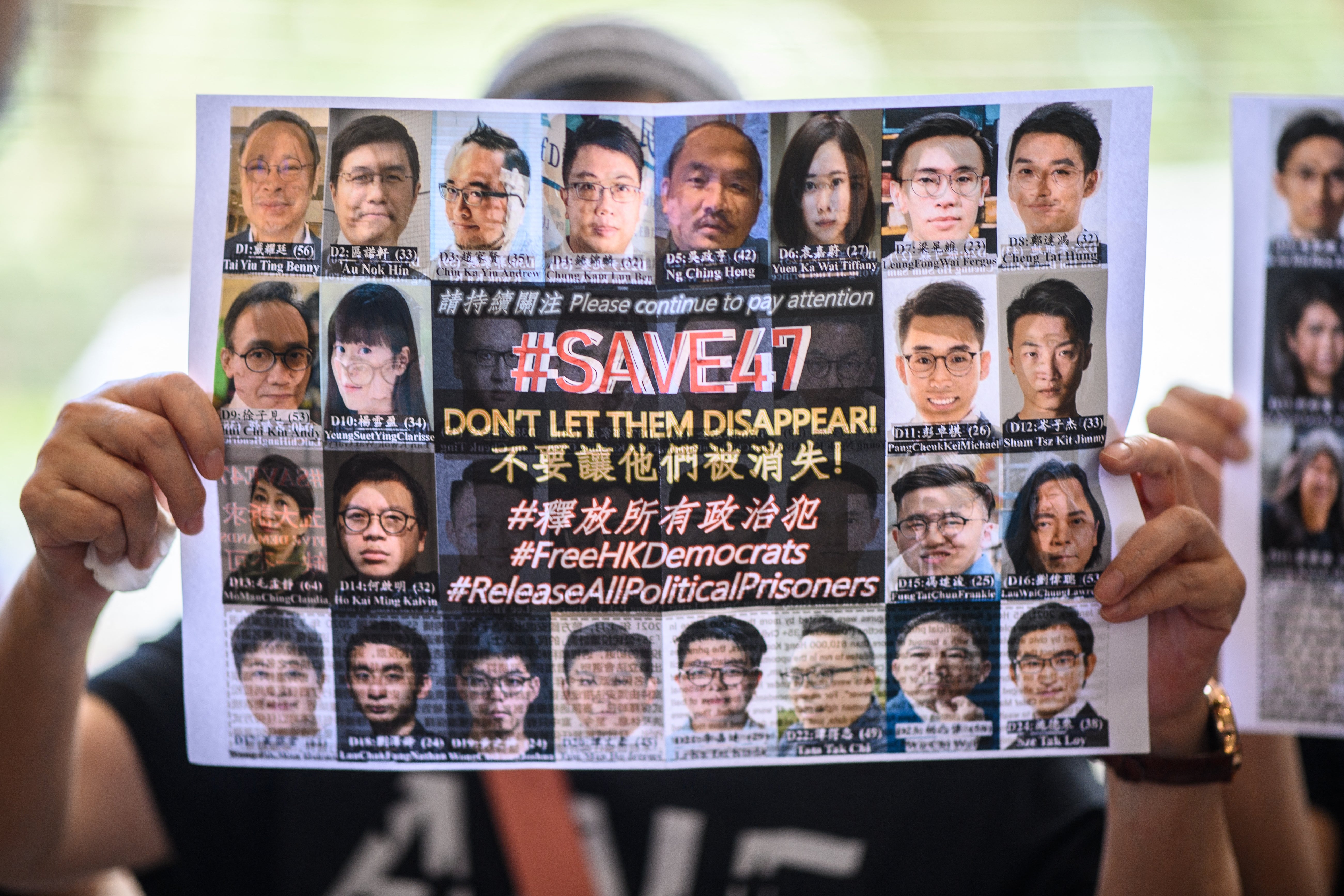 File. A supporter holds a poster showing some of the 47 pro-democracy activists on trial at the West Kowloon Court in Hong Kong on 8 July 2021