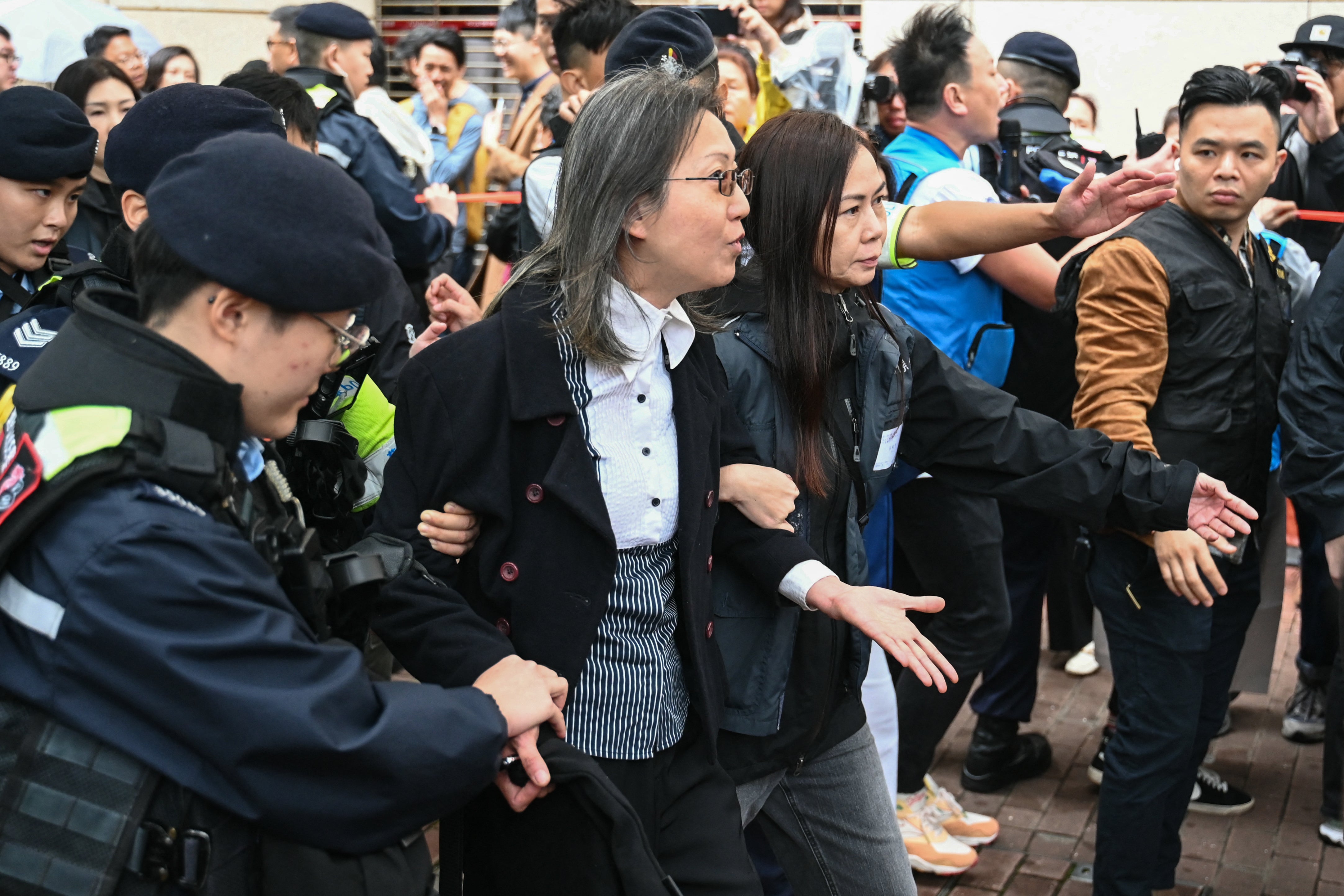 Police detain a woman outside the Hong Kong High Court ahead of sentencing in the national security case on 19 November 2024