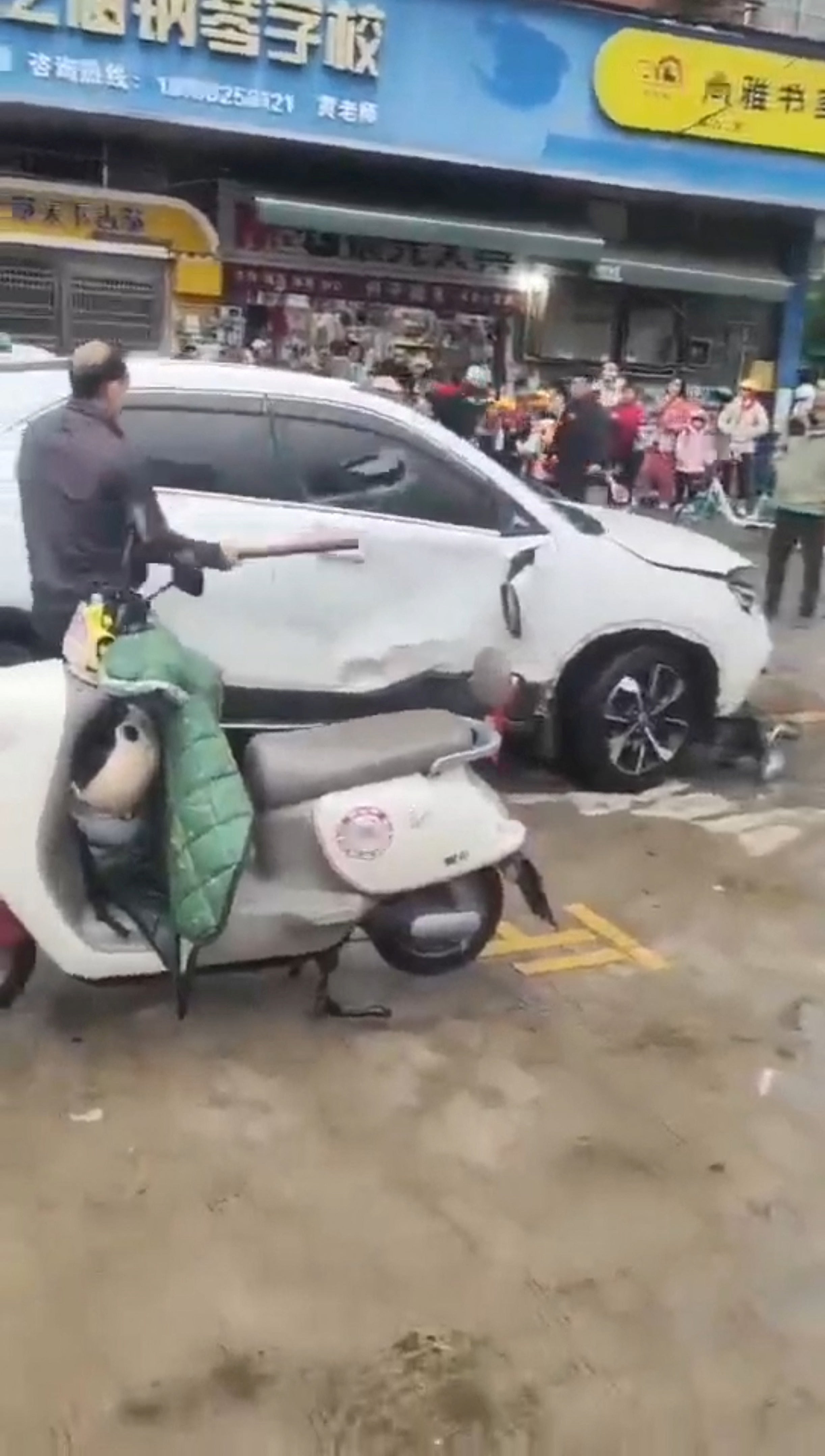 A man breaks the SUV’s window following the crash outside a primary school in Changde