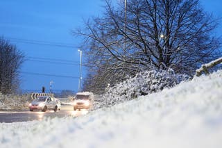 Cars drive through the snowy conditions in Carr Gate, West Yorkshire