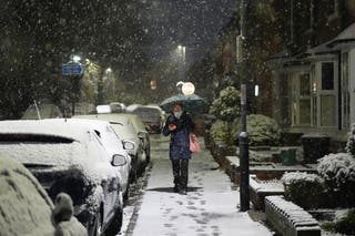 A woman walks through snow in Warwick as the UK braces for travel chaos