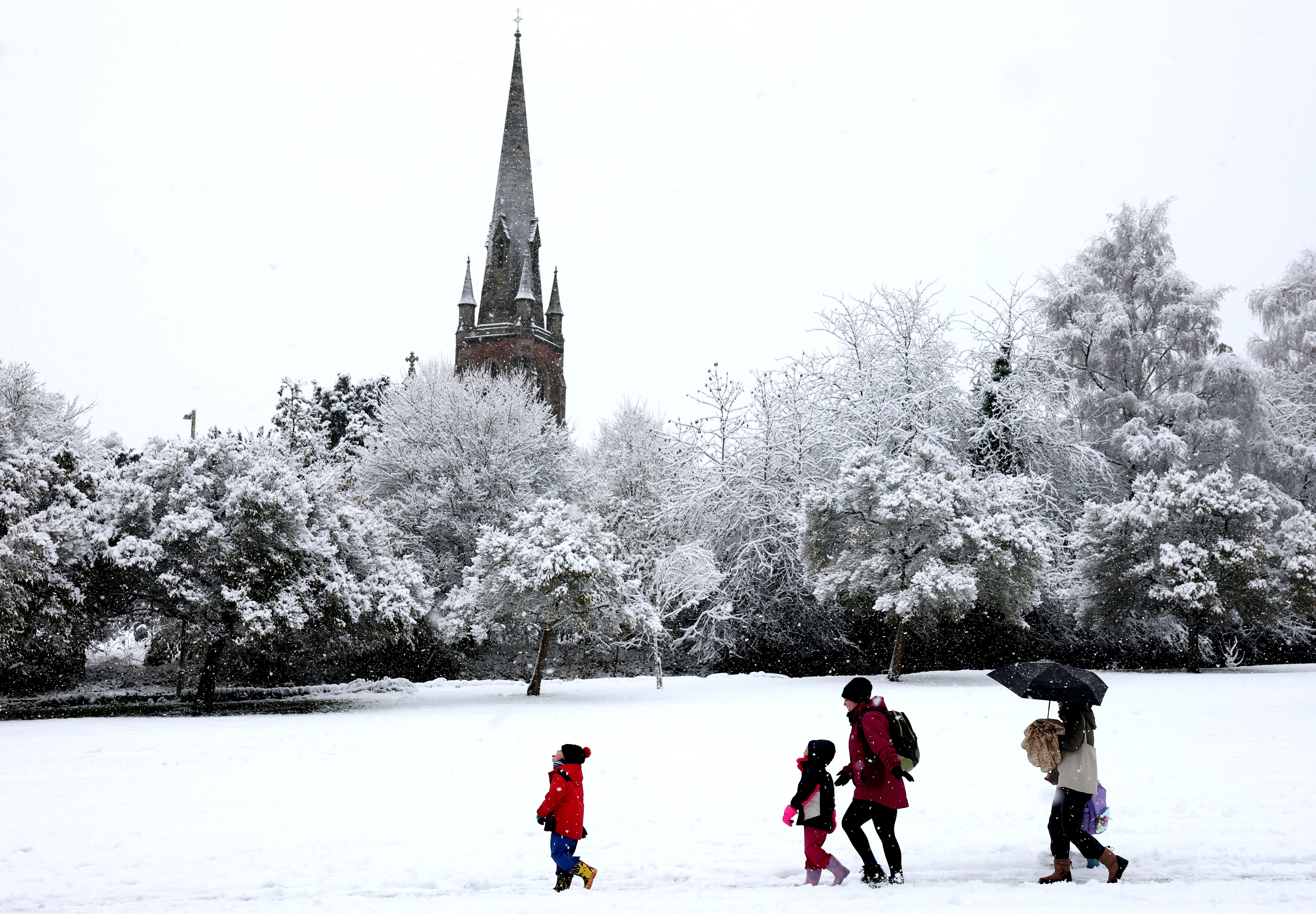 A family walk past the snow-dusted St John’s Parish Church in Keele on Tuesday morning