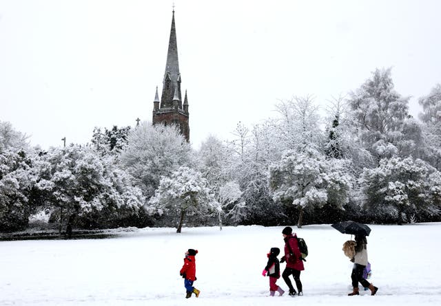 <p>A family walk past the snow-dusted St John’s Parish Church in Keele on 19 November </p>