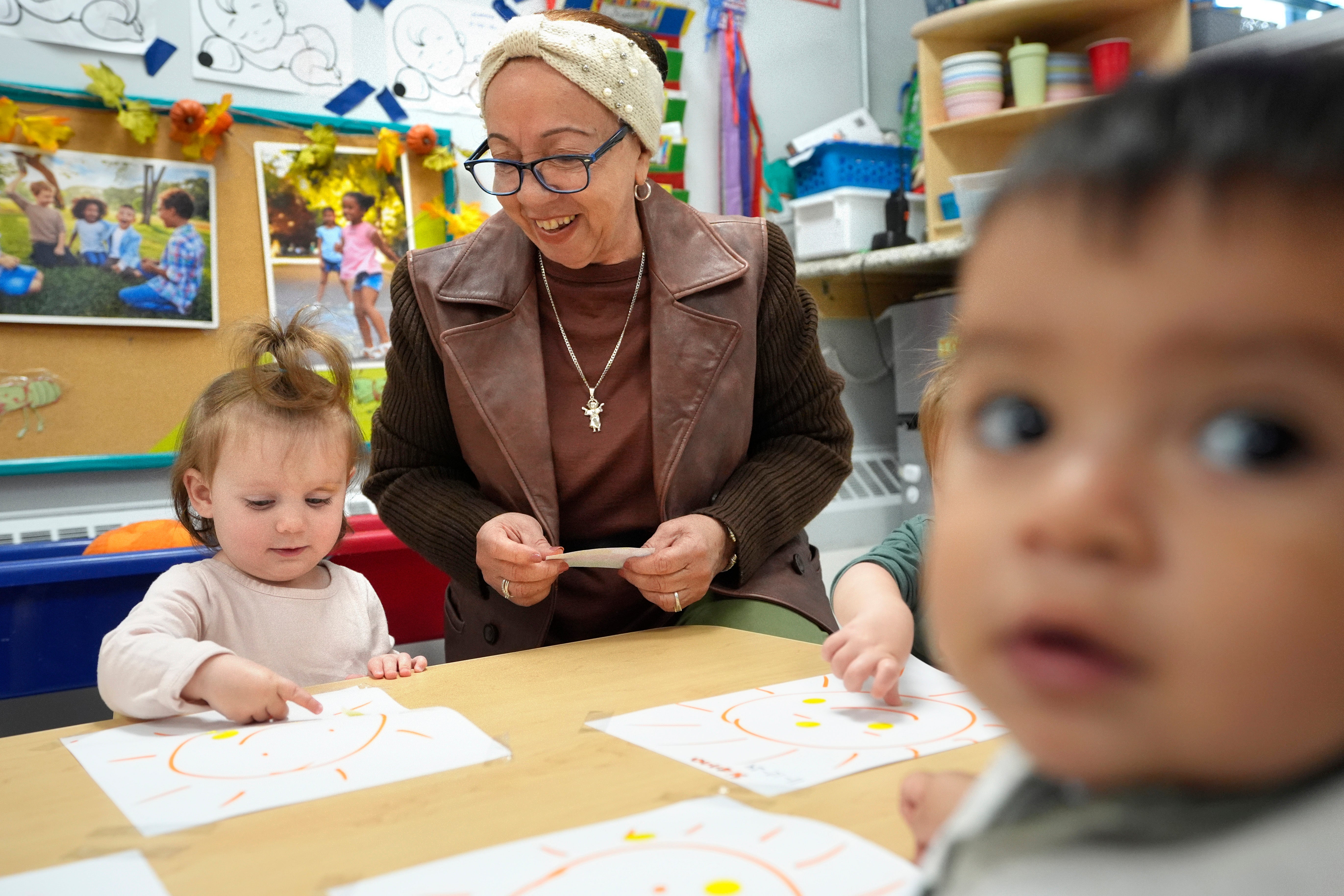 Volunteer Victoria Vasquez, 70, of Providence, R.I., center, supervises one-and-a-half year olds Scarlett Thomas, left, and Liam Echevarria Gaytan, right, in an early childcare program at Federal Hill House.