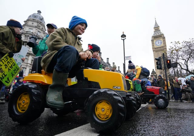 <p>Children ride on toy tractors as part of the farmers’ protest in central London</p>