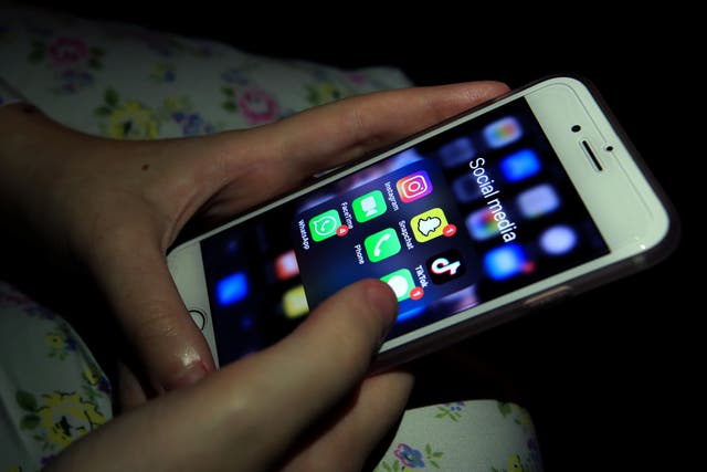 A young girl looks at social media apps on a phone (Peter Byrne/PA)