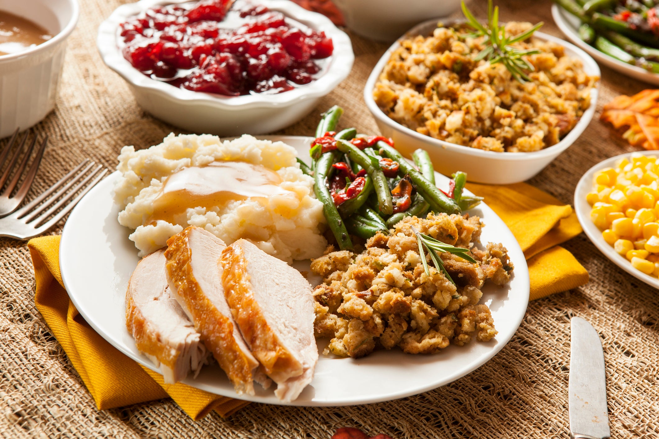 A plate is full of Thanksgiving food, including turkey, green beans, mashed potatoes, and stuffing. Climate change to hit the agriculture industry in coming years, leading to shortages of the crops that make up favorite dishes