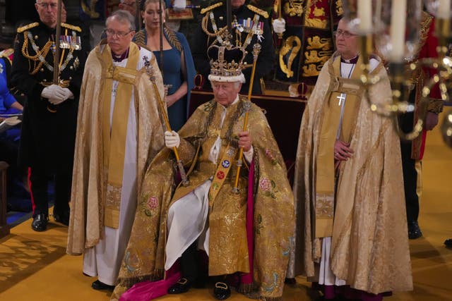 The King seated in St Edward’s Chair, also known as the Coronation Chair, wearing St Edward’s Crown and holding The Sovereign’s Sceptre with the Dove (in his left hand) and The Sovereign’s Sceptre with Cross (in his right hand) (Aaron Chown/PA)