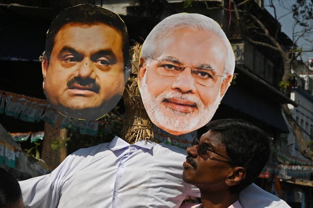 <p>A supporter of India’s Congress party carries an effigy of prime minister Narendra Modi and tycoon Gautam Adani </p>