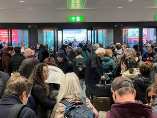 Queues of passengers wait to board the shuttle from the north terminal to the reopened south terminal