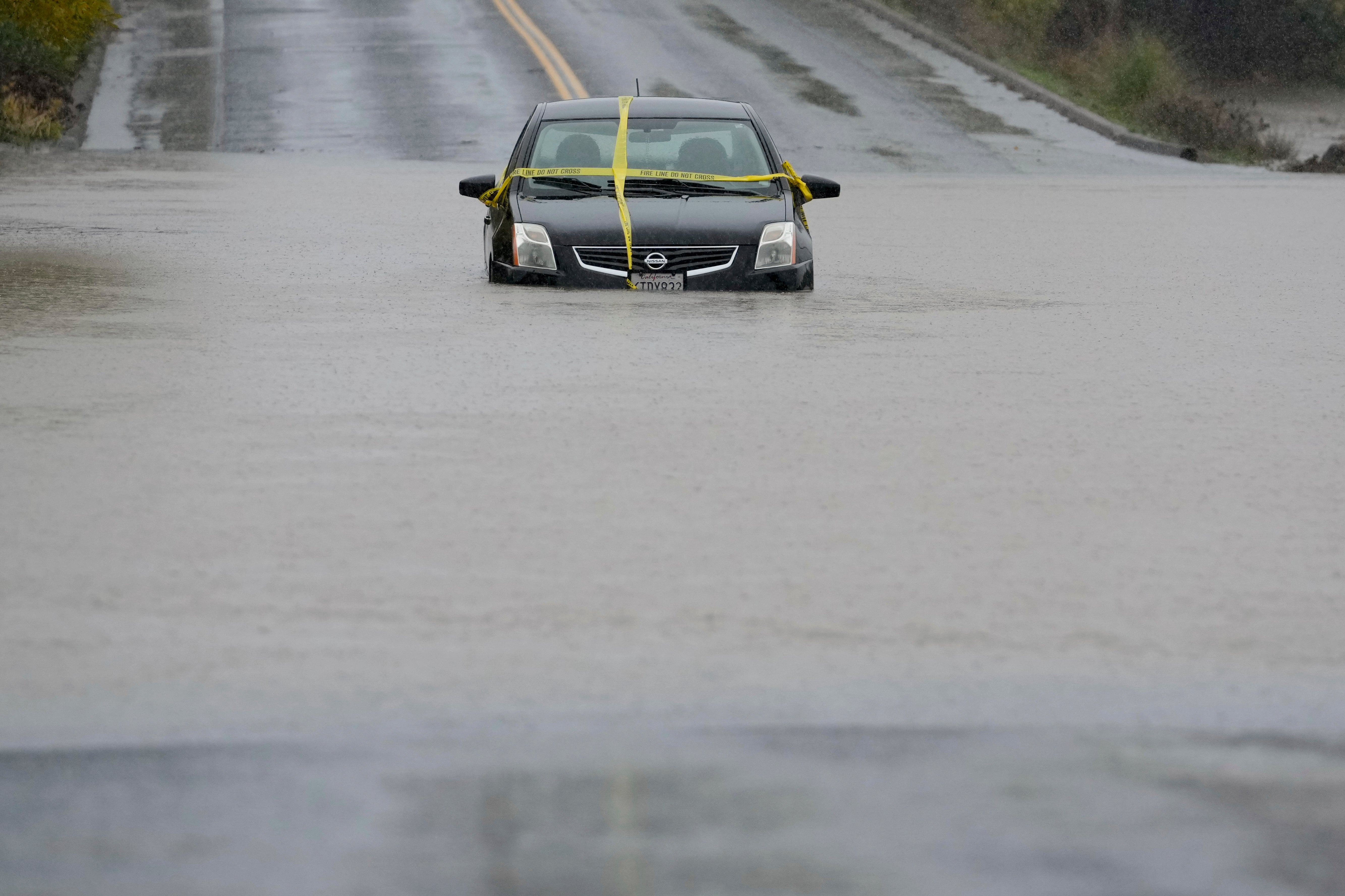 A car is seen stranded on a flooded road in Windsor, California, on Thursday. Flooding rainfall forced evacuation orders in parts of California