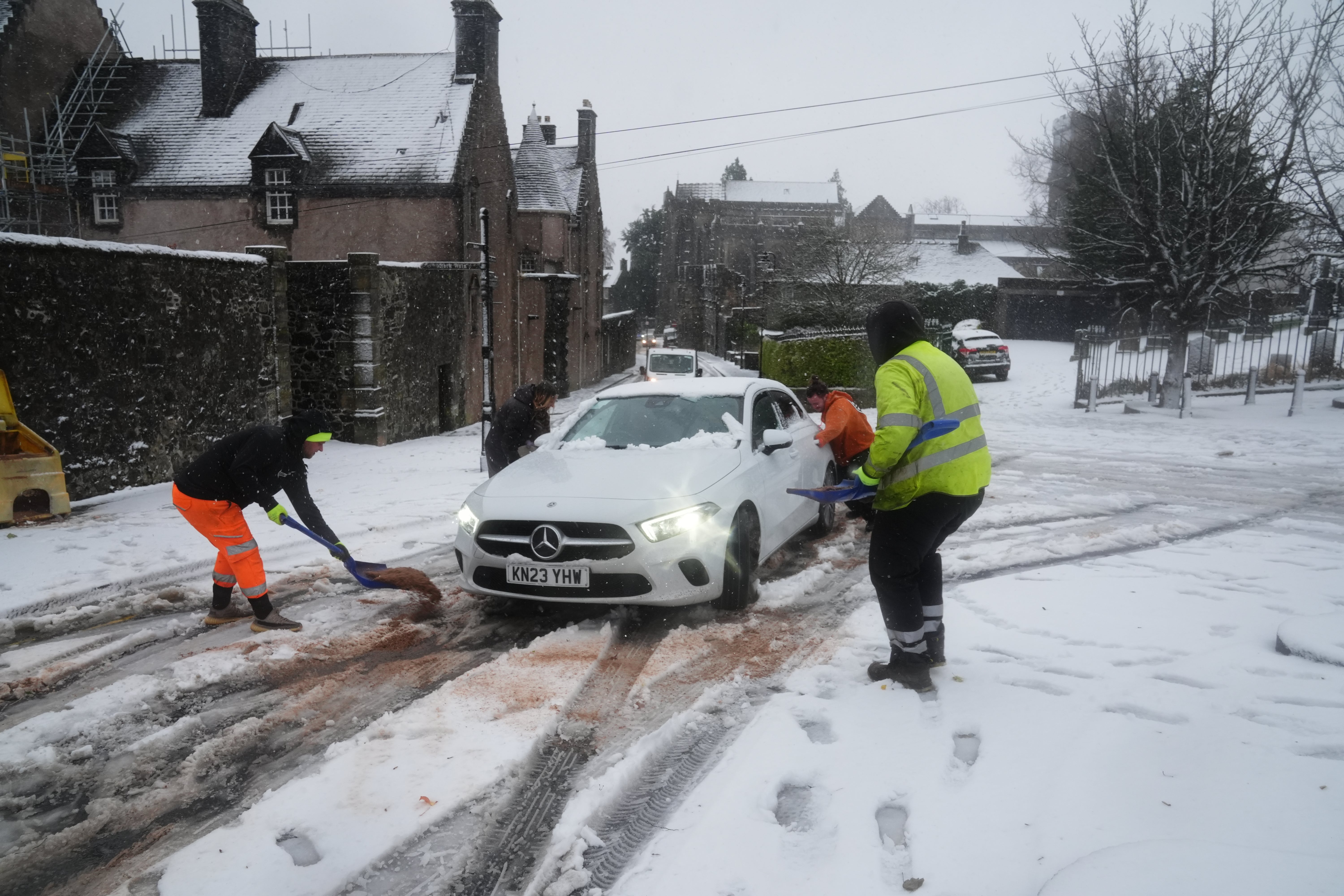 People help a driver in the snow in Stirling, Scotland, during Storm Bert on Saturday